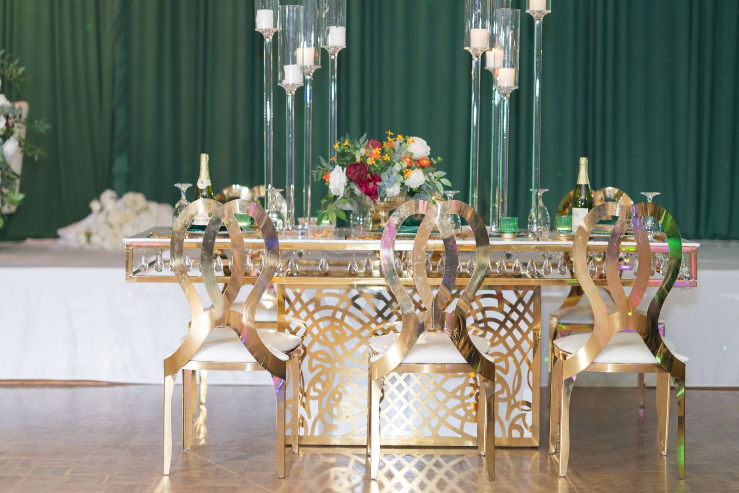 Luxurious gold geometric wedding table decor with tall glass candle holders and floral centerpieces.
