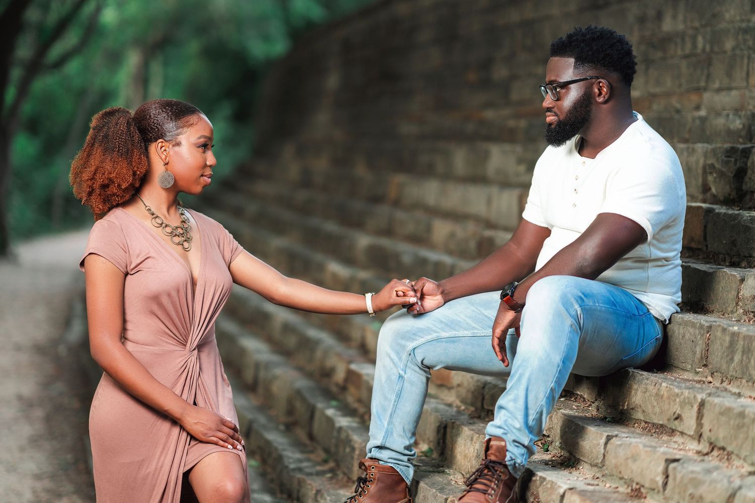A couple sits together on stone steps having an intimate conversation.