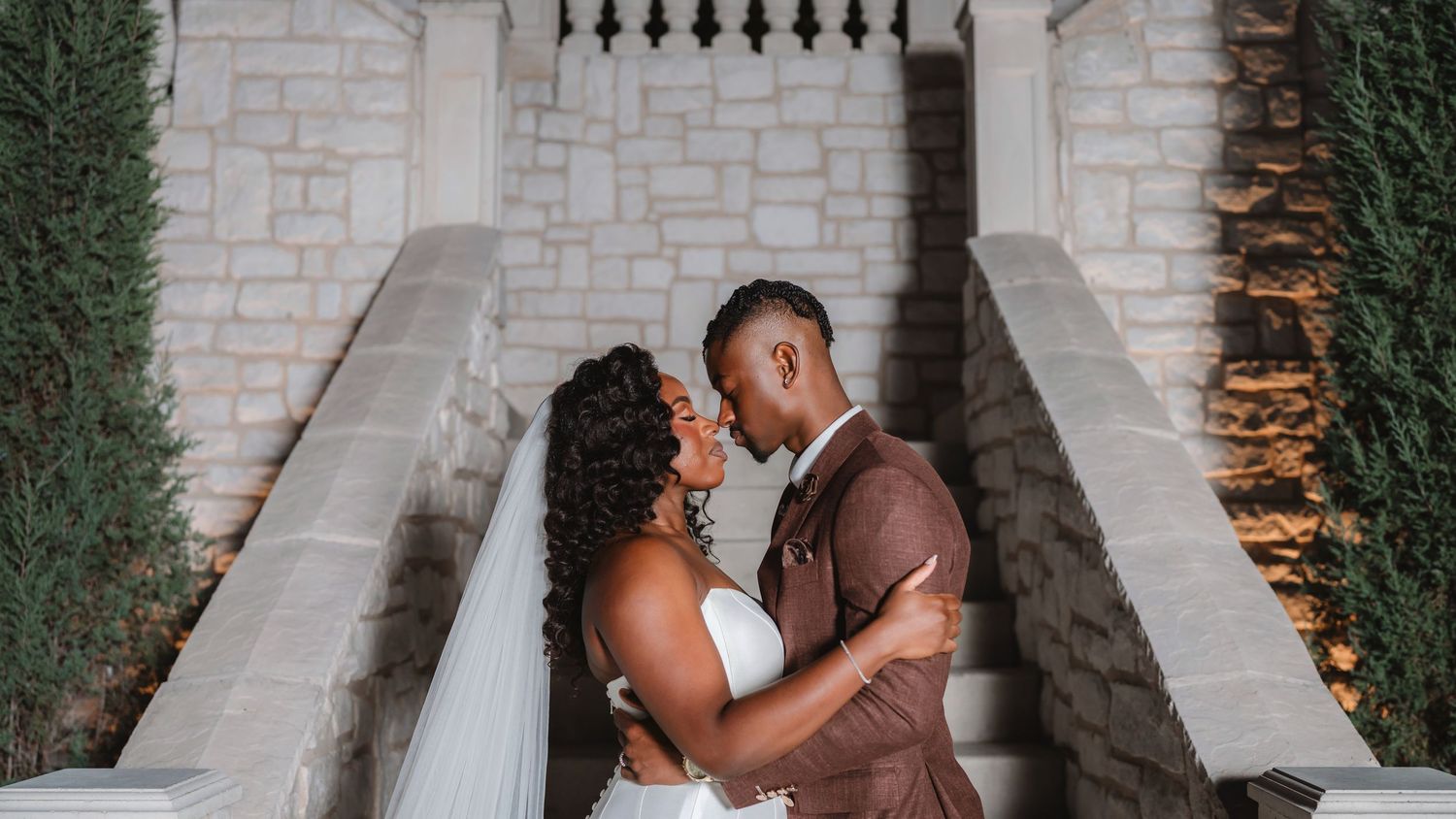 Intimate wedding couple moments captured against stone architecture and greenery.