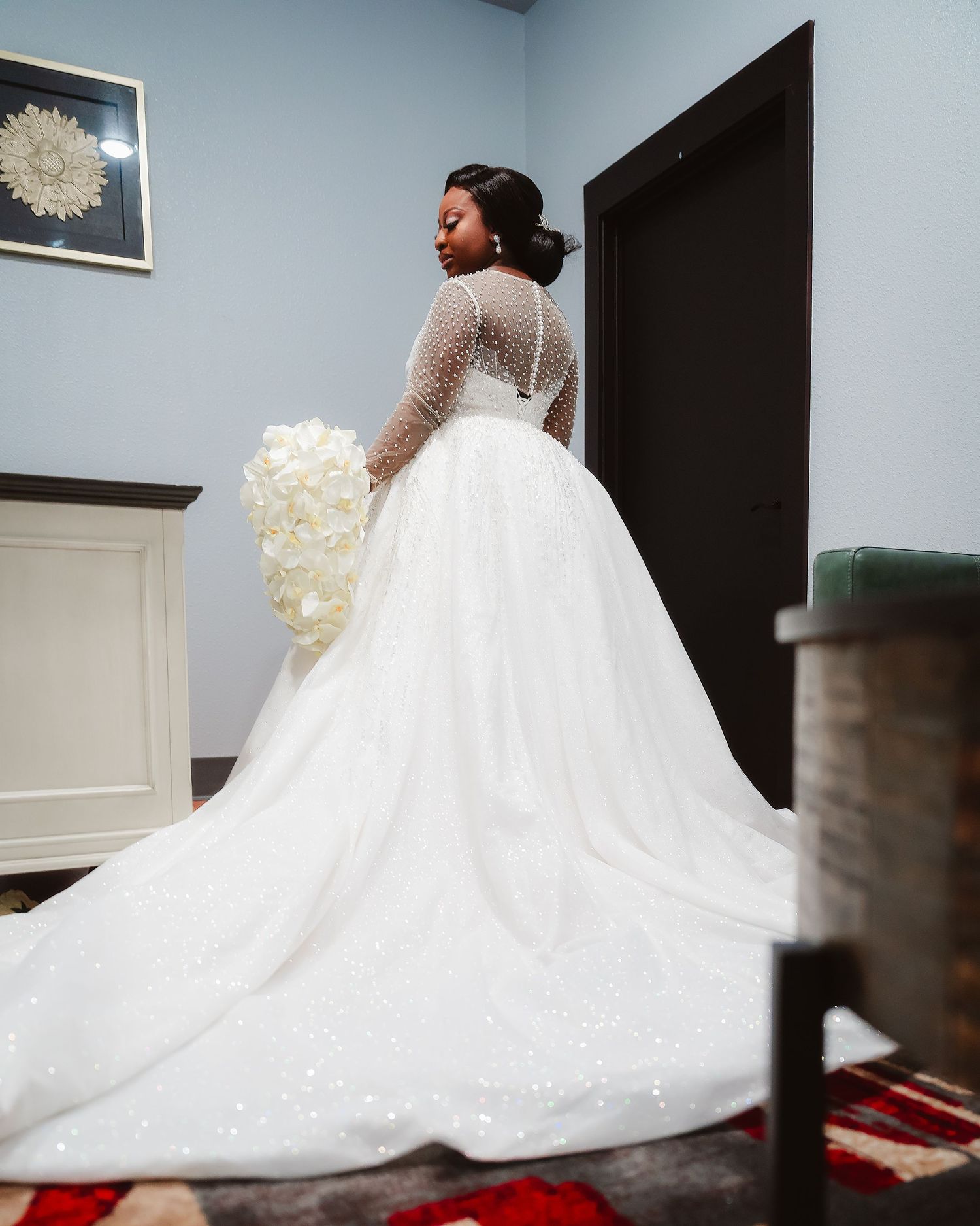 A stunning white wedding gown with a dramatic flowing train displayed against a dark background.