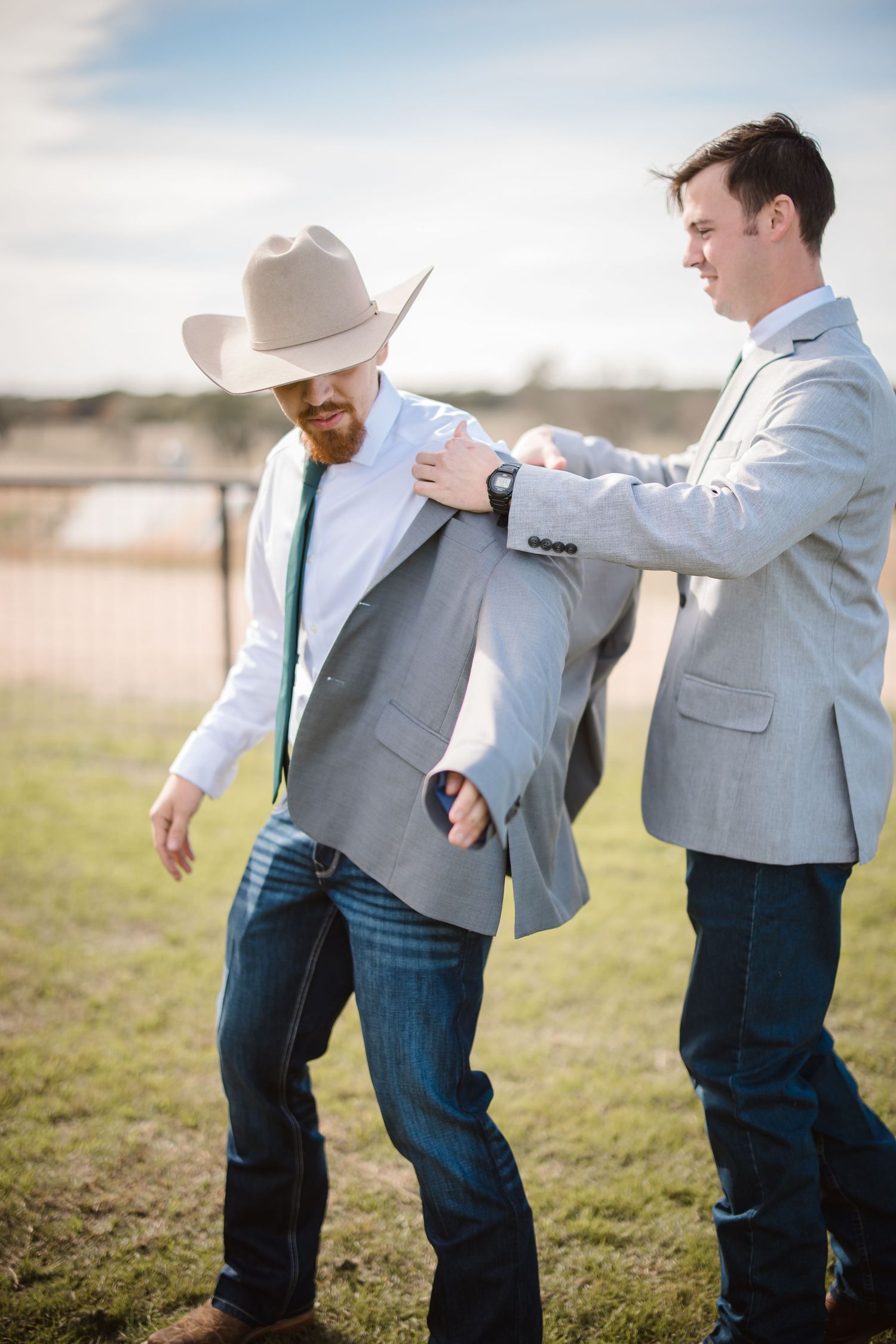 Playful sequence of groomsmen in gray suits and cowboy hats goofing around in a grassy field.