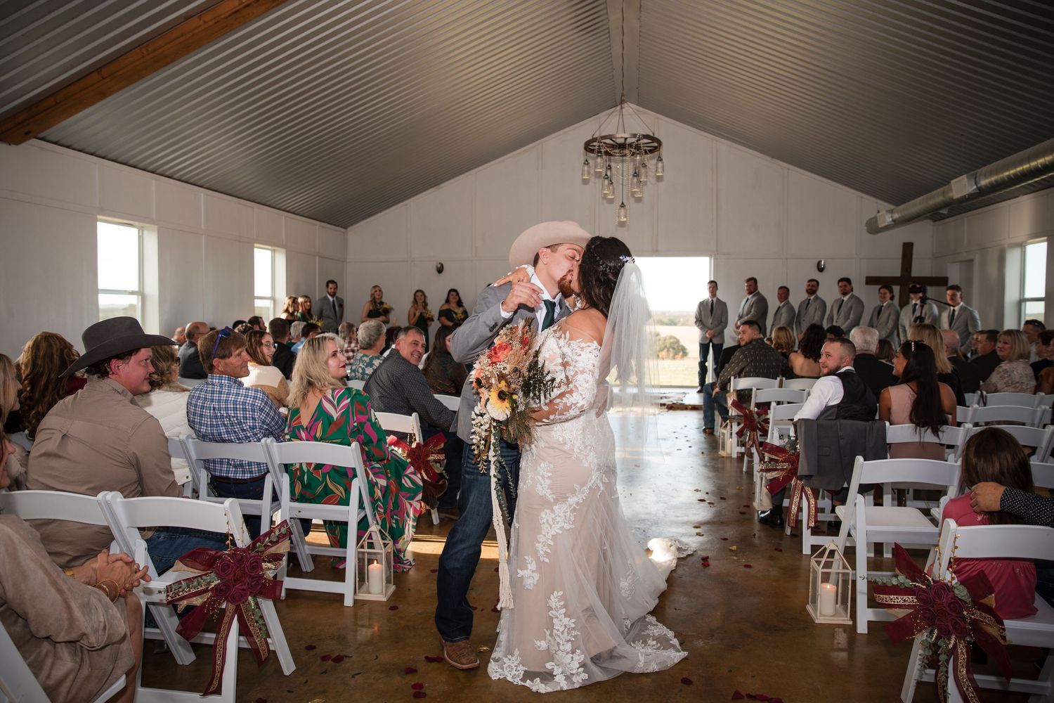 Wedding reception celebration inside a rustic venue with wooden ceiling beams and festive decorations.