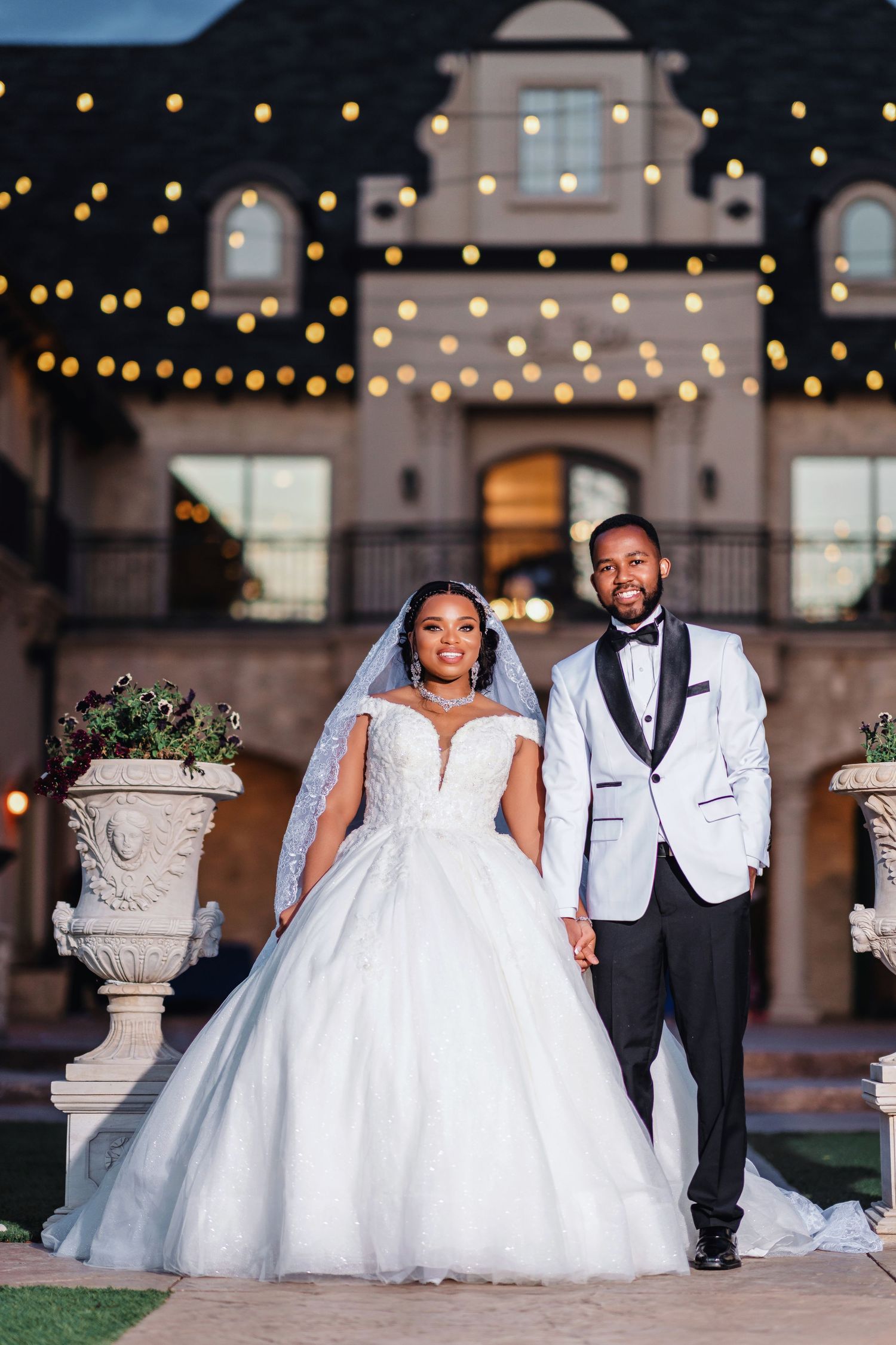 Elegant evening wedding photos with twinkling lights and formal attire against architectural backdrop.
