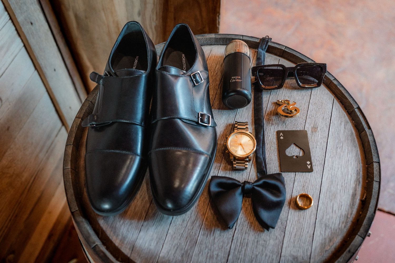 Collection of formal black leather shoes and accessories arranged on wooden floor.