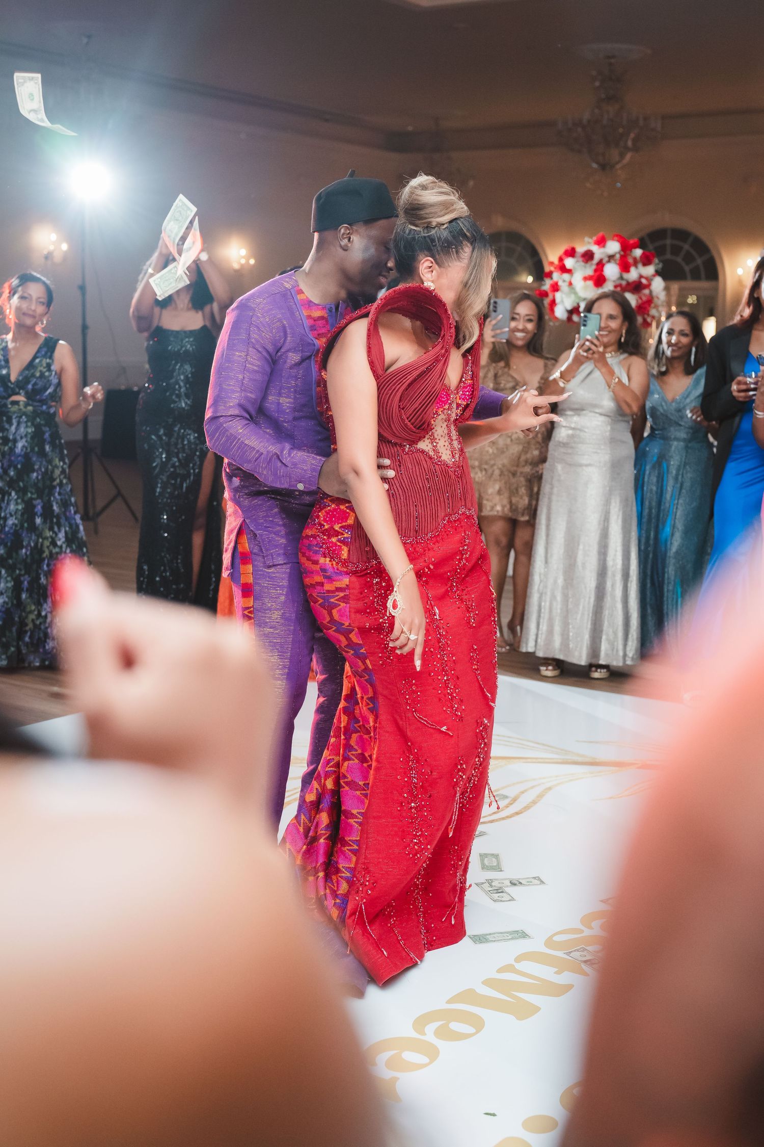 Couple dancing at a wedding reception with guests watching in the background.