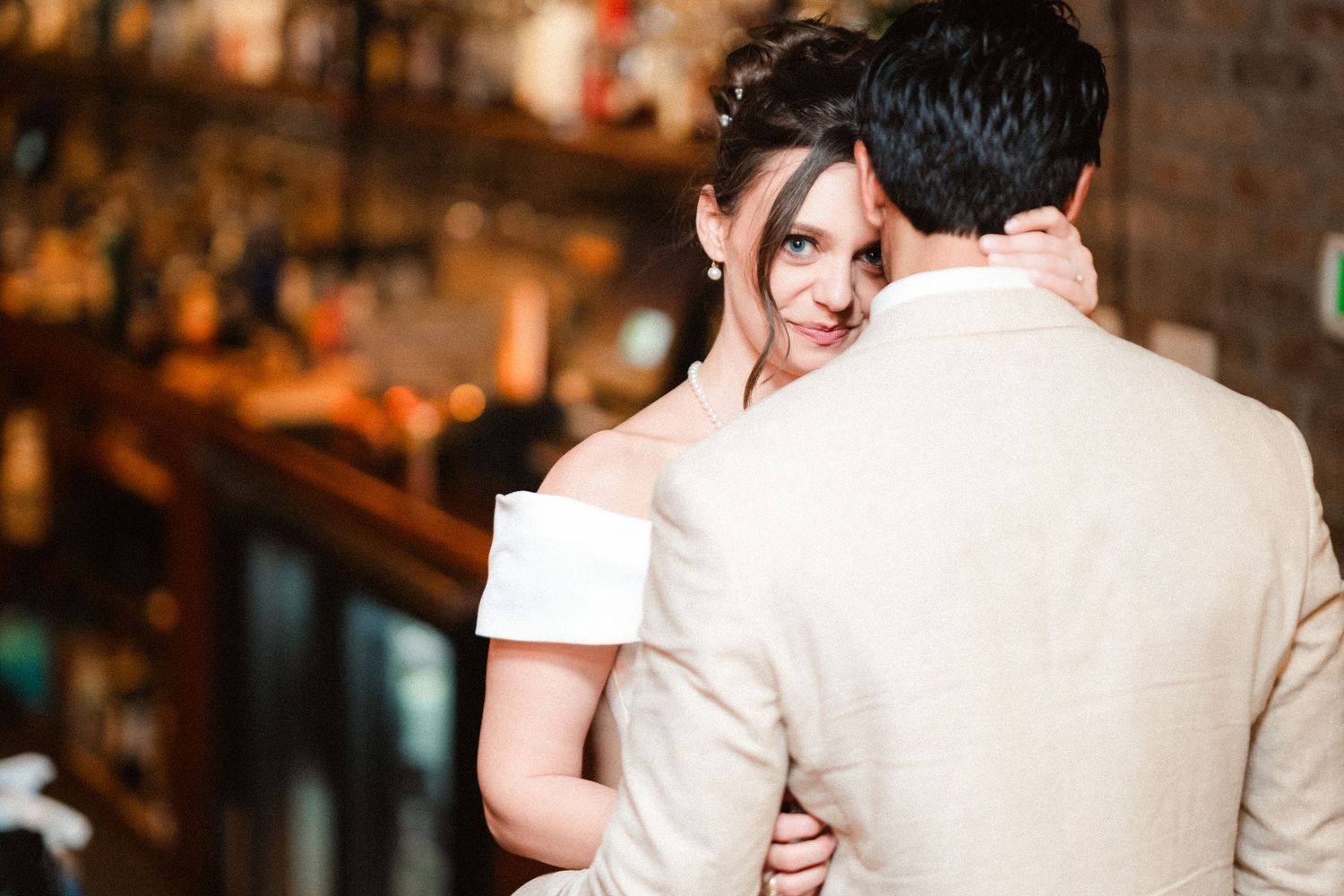 A couple in formal attire embraces during a romantic dance at a wedding reception.