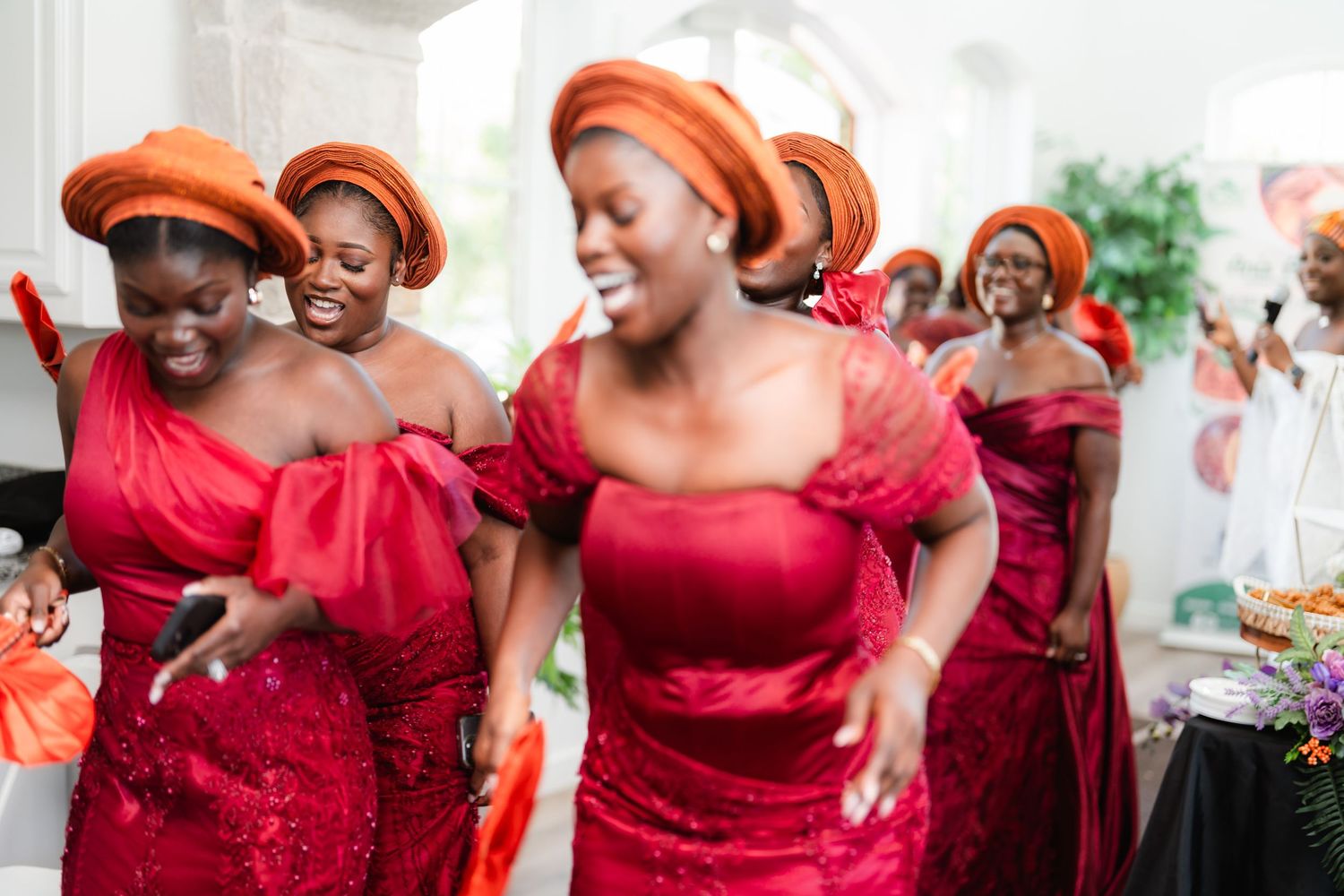 Wedding party wearing matching deep red dresses celebrating joyfully together.