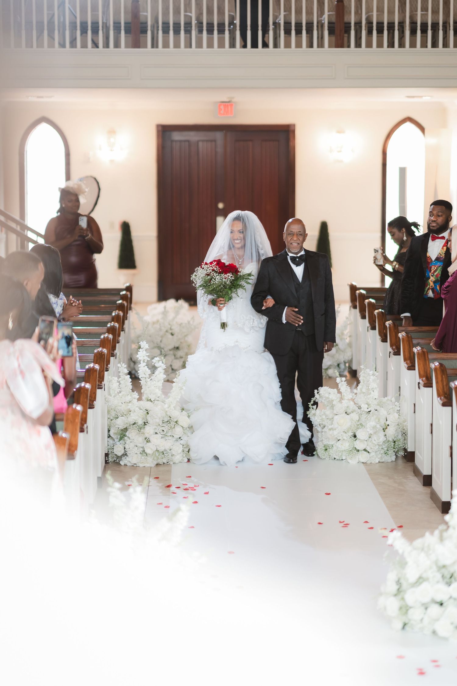 Wedding ceremony setup in a church with white floral arrangements lining the aisle.