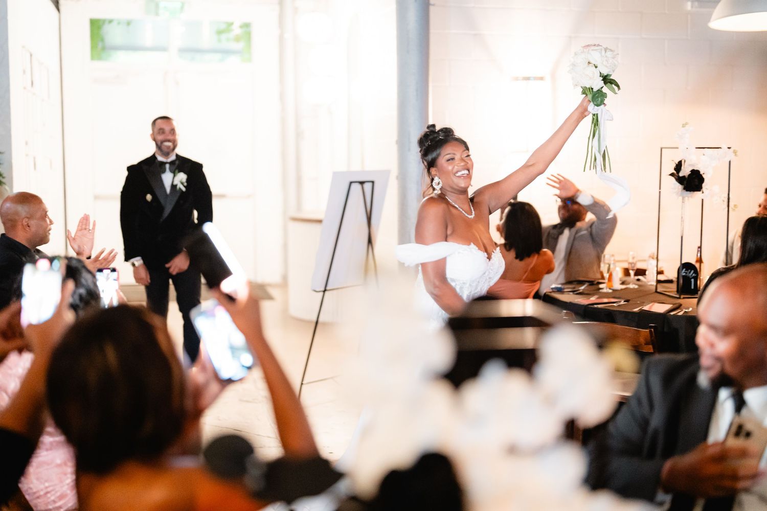 Wedding reception guests raise glasses in celebration during a toast.