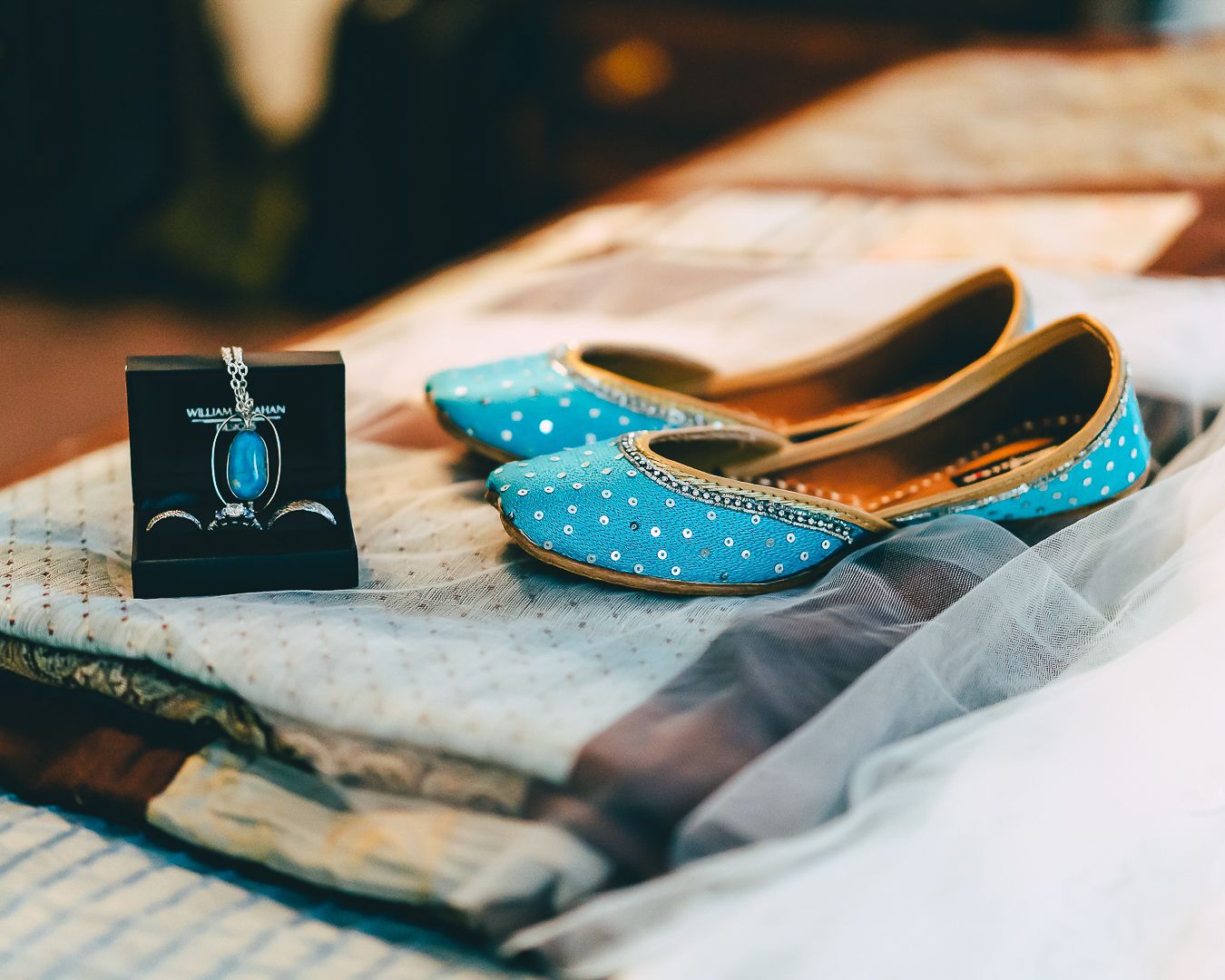 Elegant turquoise bridal shoes arranged with delicate fabrics and wedding accessories in a soft natural light setting.