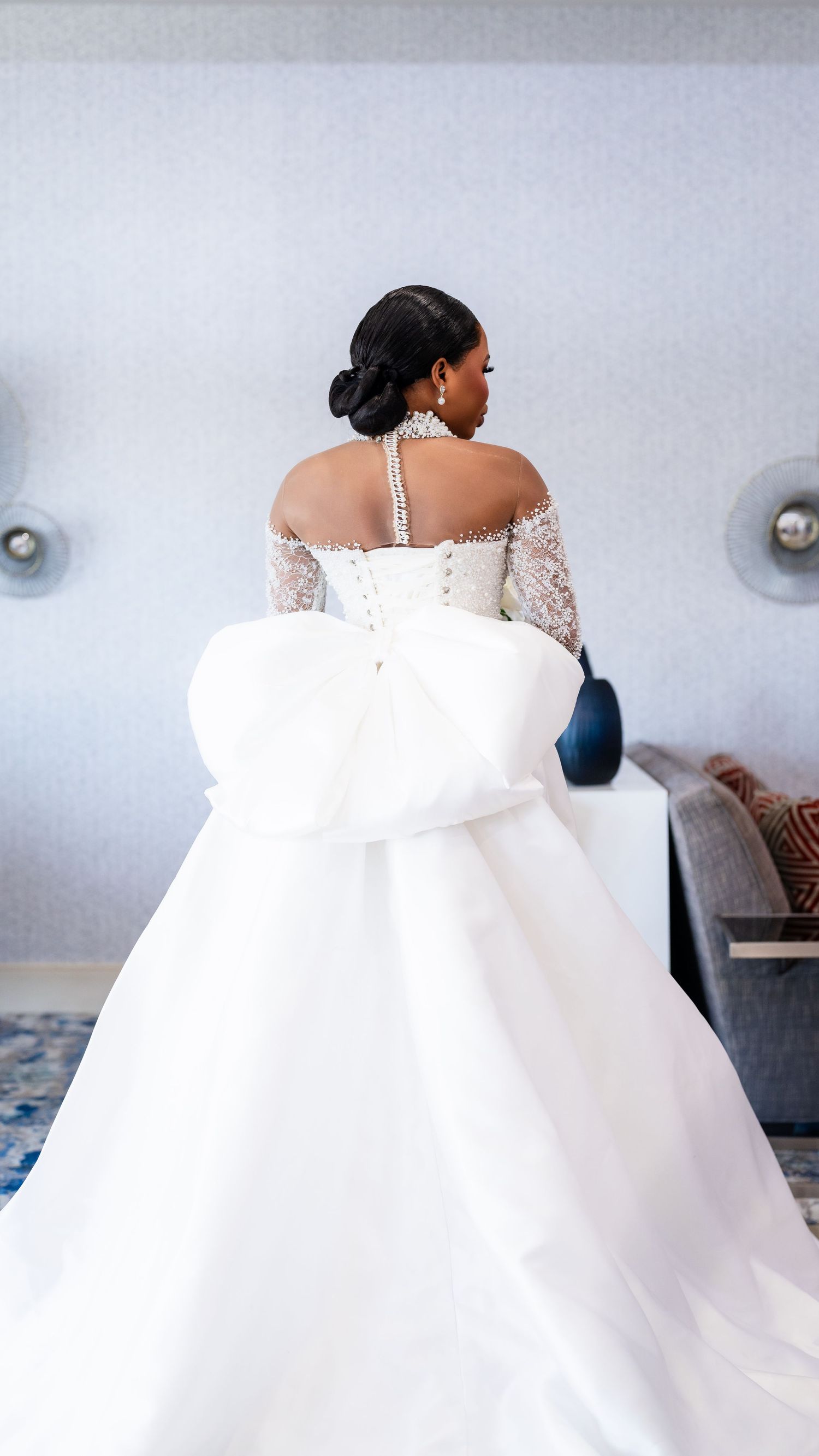 Elegant white wedding gown with off-shoulder lace details and dramatic train shown from behind.