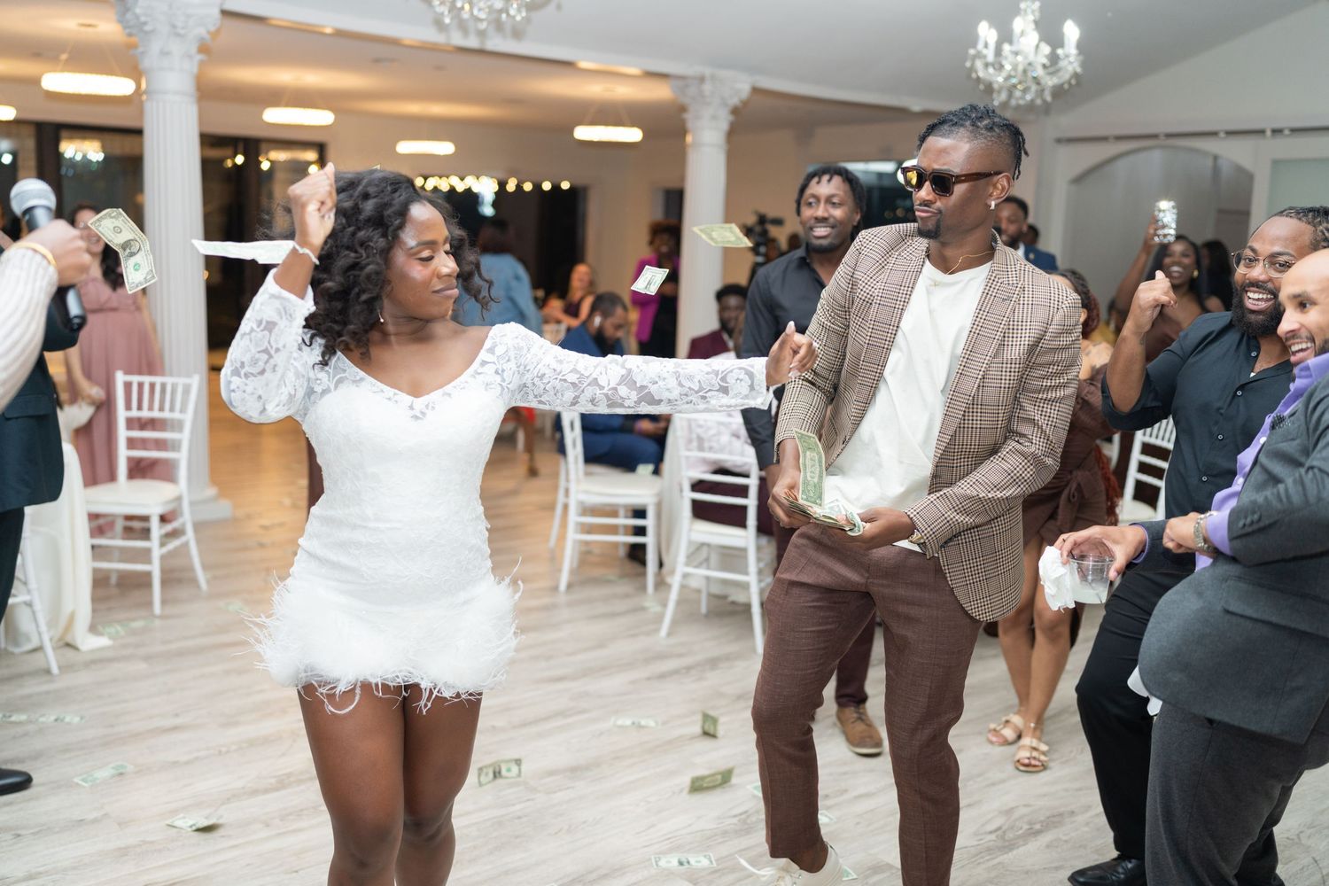 Wedding reception venue decorated with chandeliers and white chairs for celebration.
