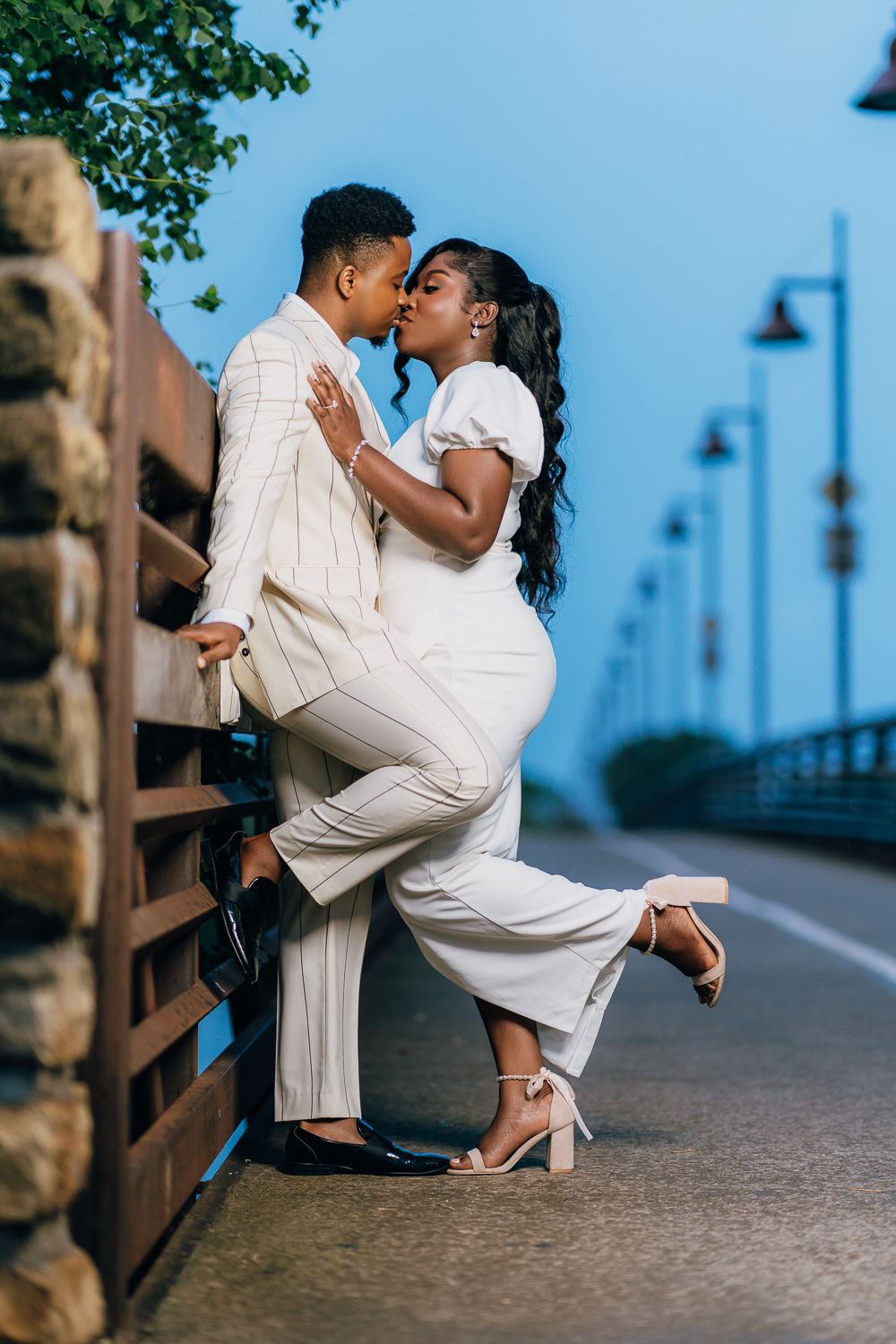 Couple in white outfits share an intimate dance pose on an outdoor pathway.