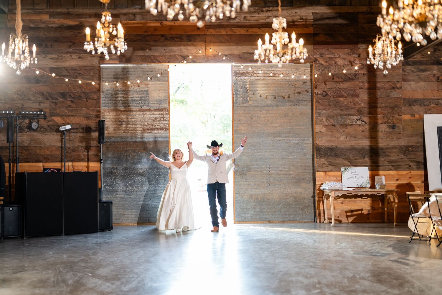 Rustic indoor wedding venue with wooden walls and elegant crystal chandeliers.