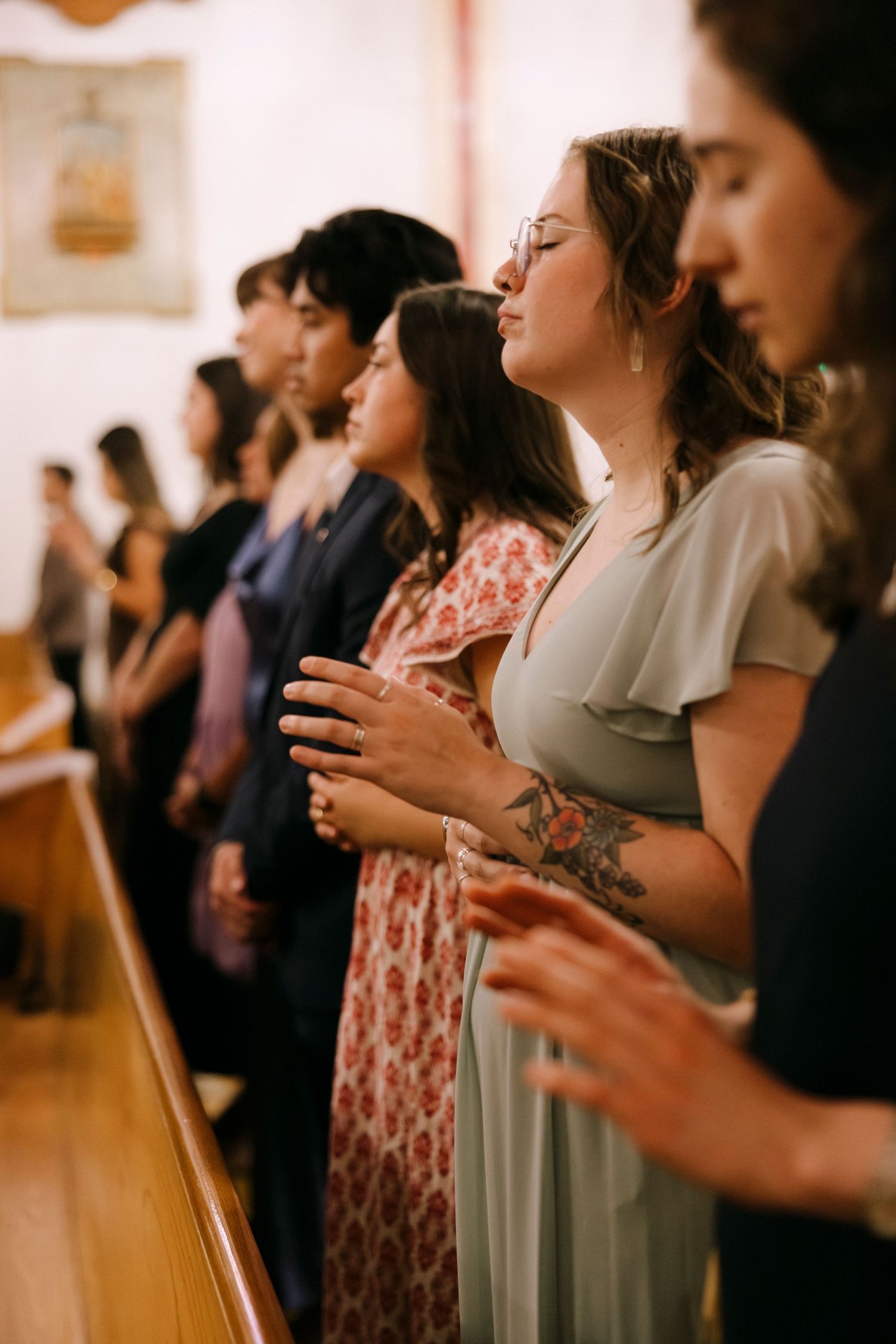 Wedding guests standing in church pews during a ceremony.