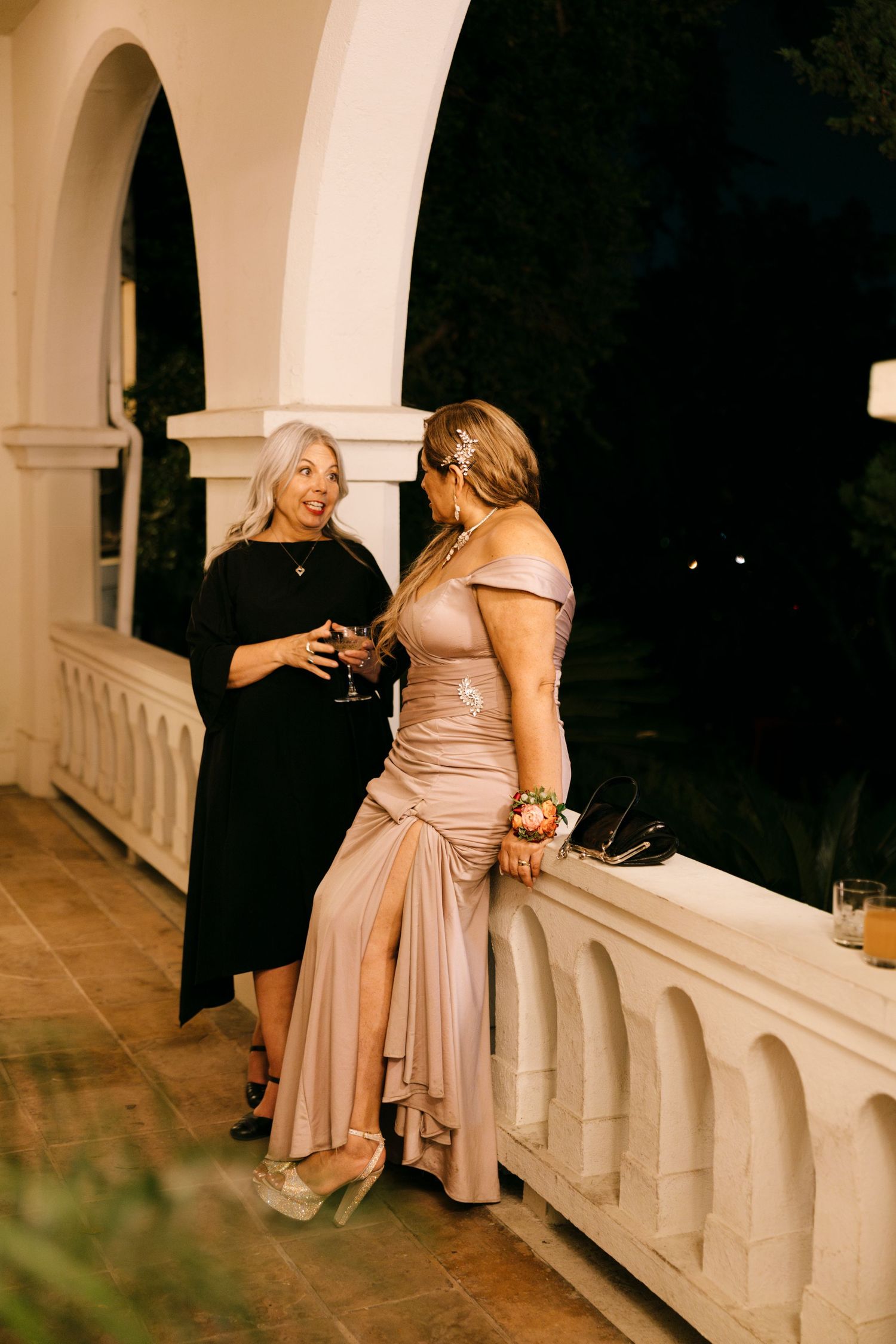 Two guests chatting on an elegant balcony during an evening celebration.