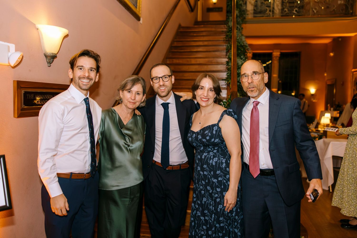 A group of party guests pose together at a formal event in evening wear.