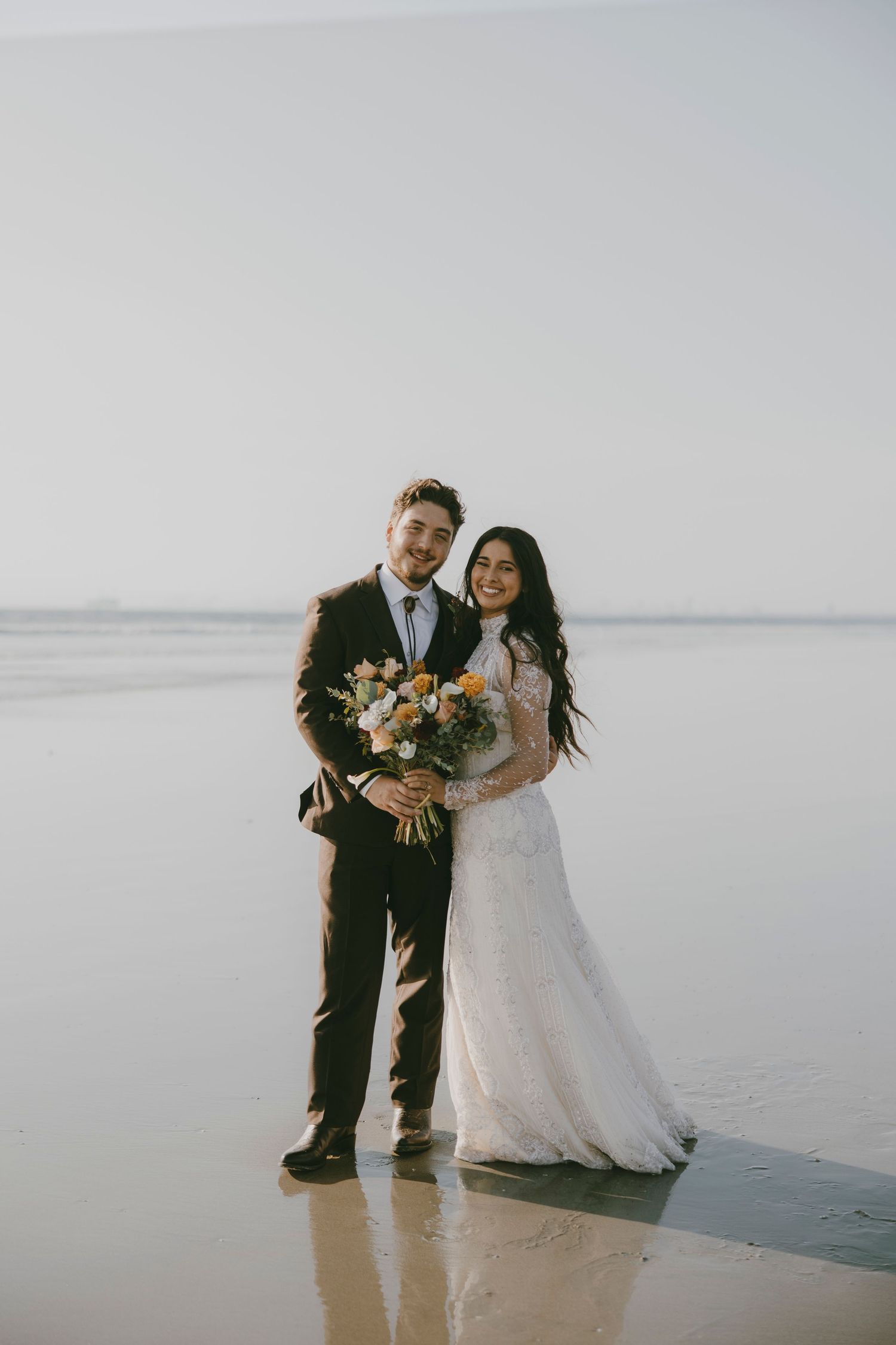 A romantic wedding photoshoot on a serene beach with sunflowers and flowing white dress.