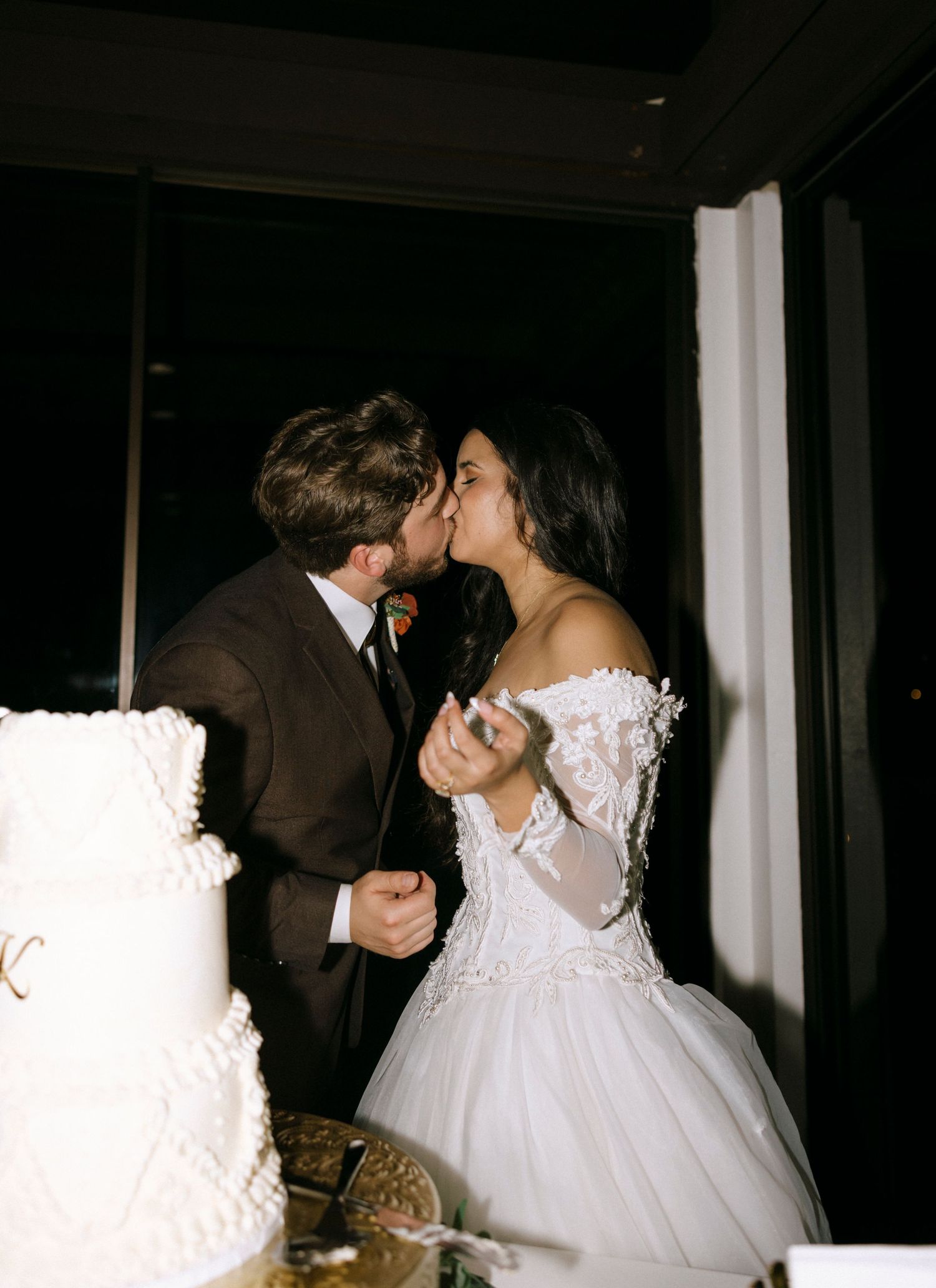Wedding couple sharing a moment near their elegant white cake display.