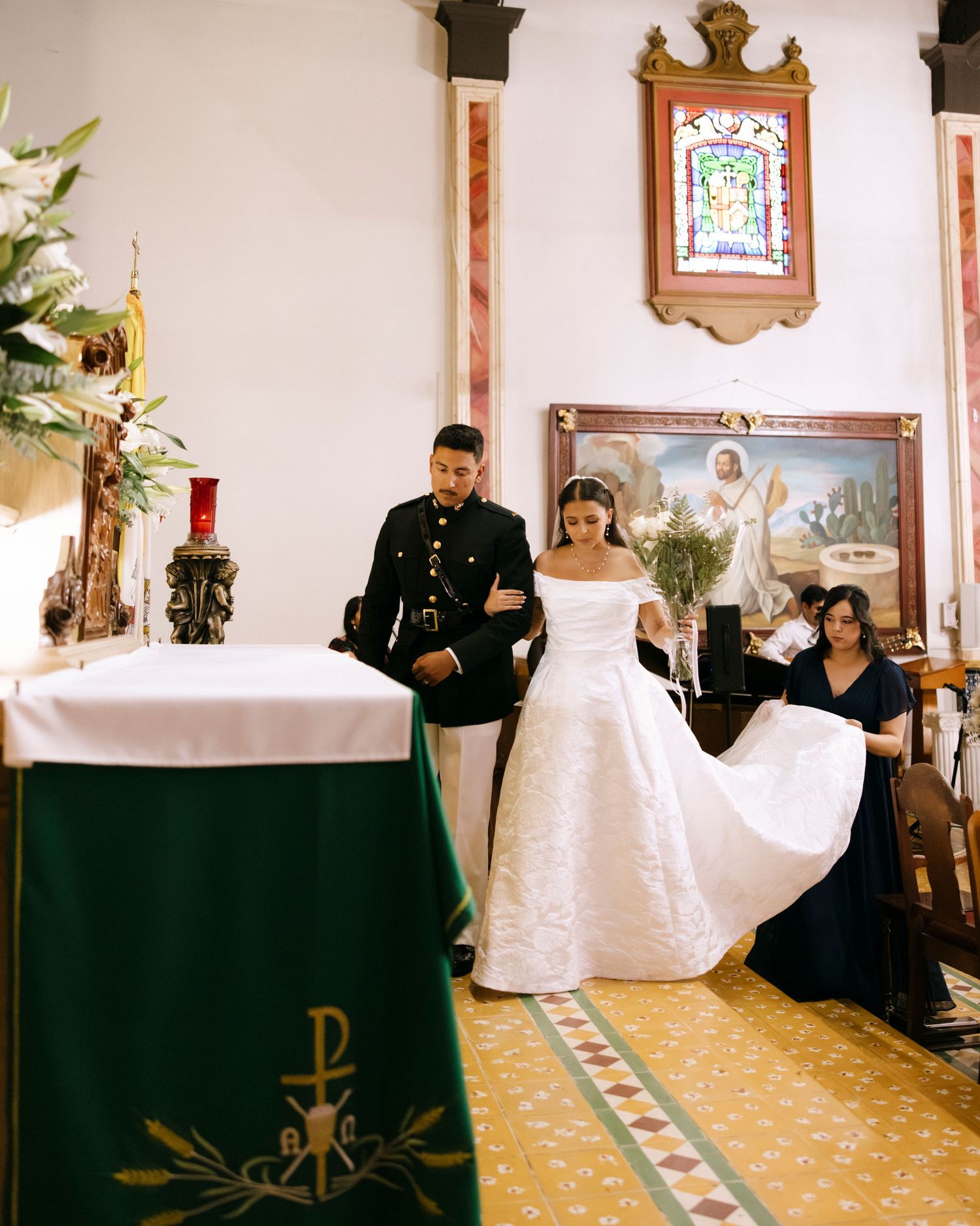 Church ceremony with white-robed figures and green altar decorations.
