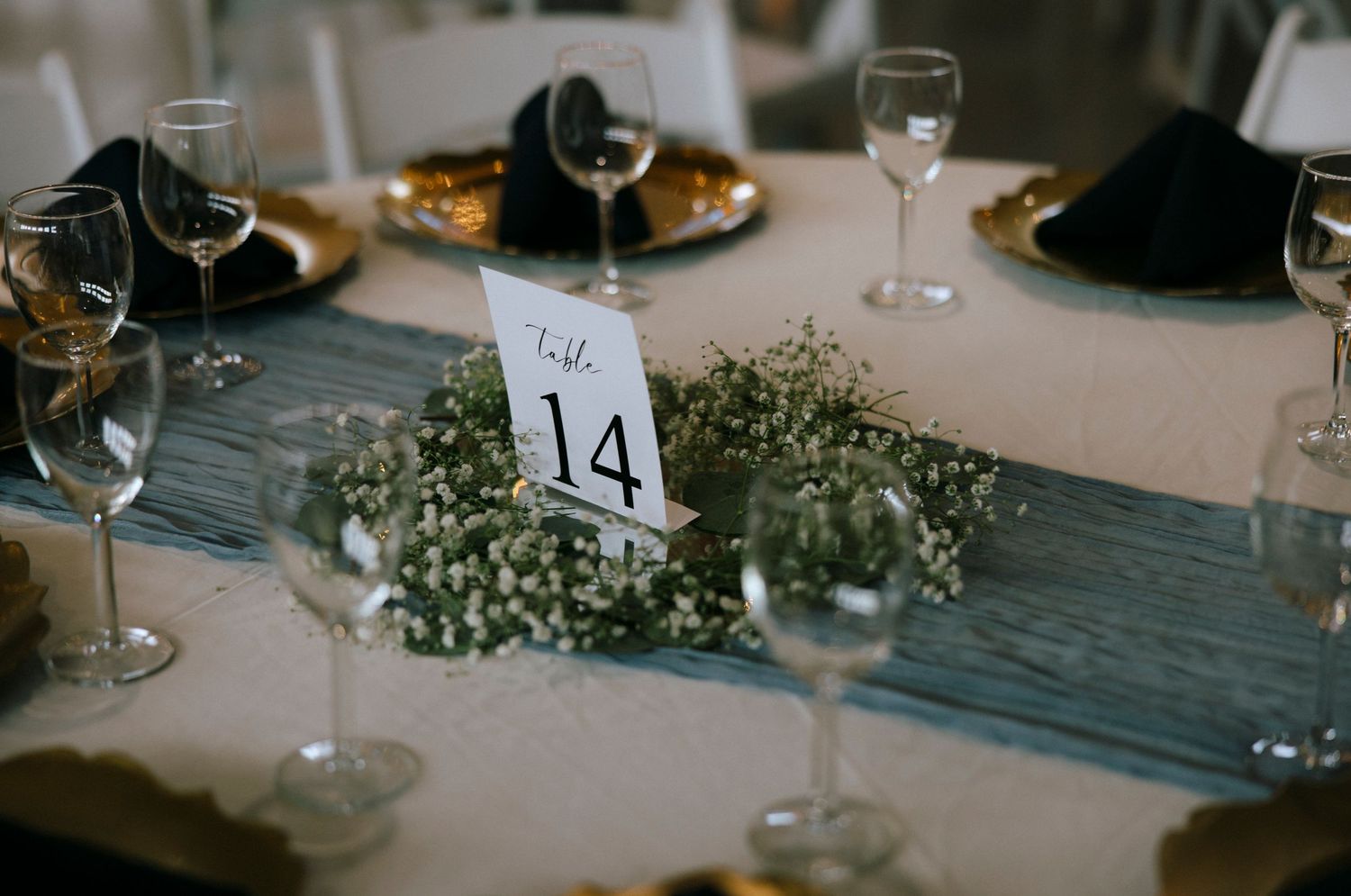 Wedding reception table setting with wine glasses and table number fourteen.