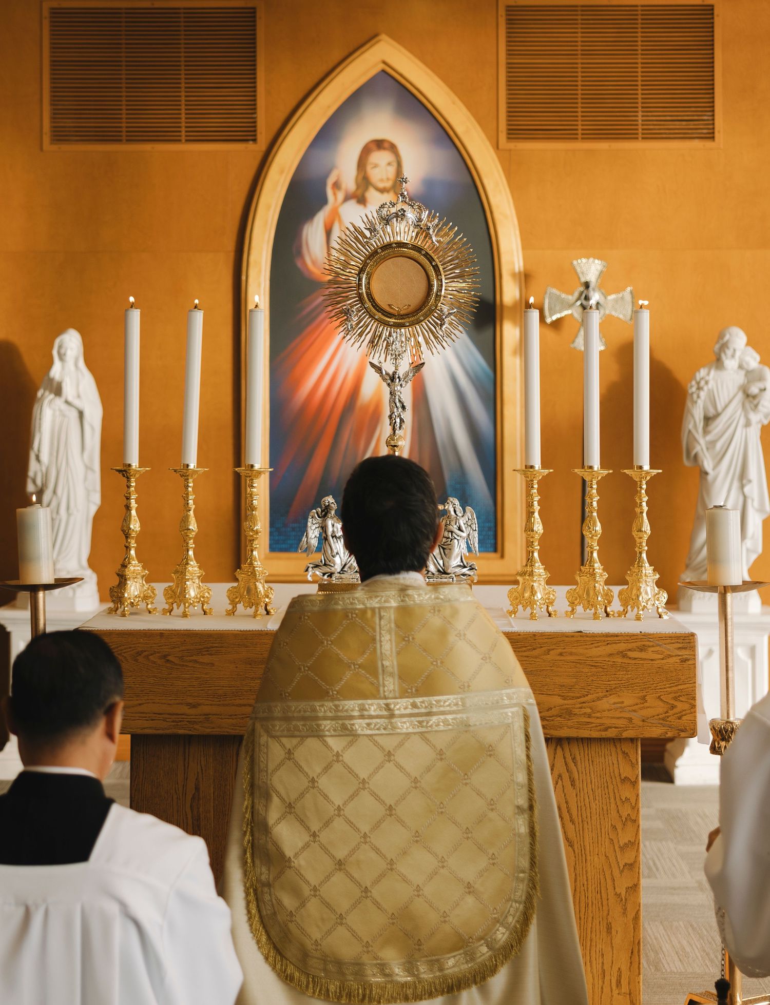 Religious altar with candles and sacred art displaying Jesus and religious imagery in golden lighting.