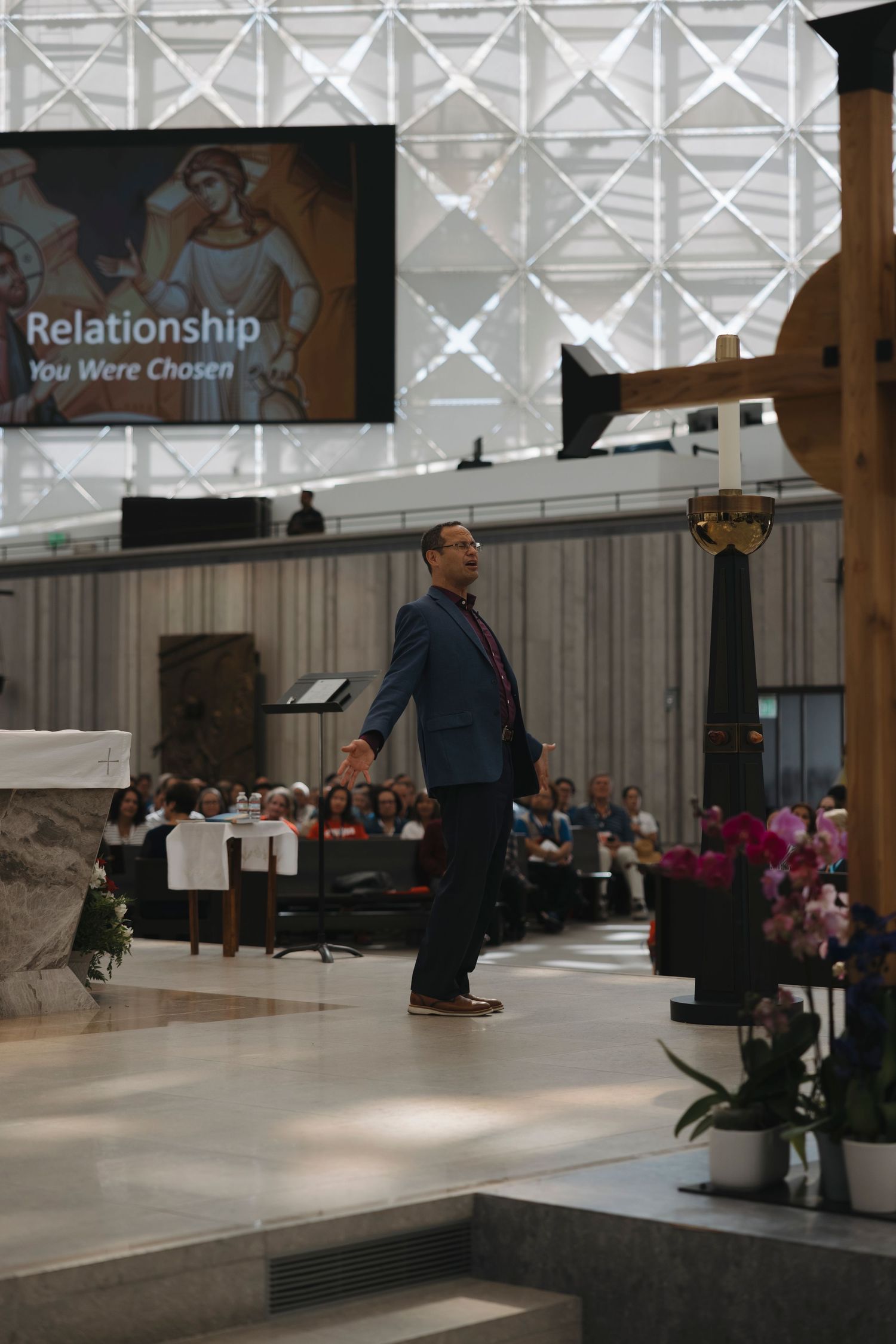 A speaker stands on stage during a presentation with 'Relationship' displayed on the screen behind.