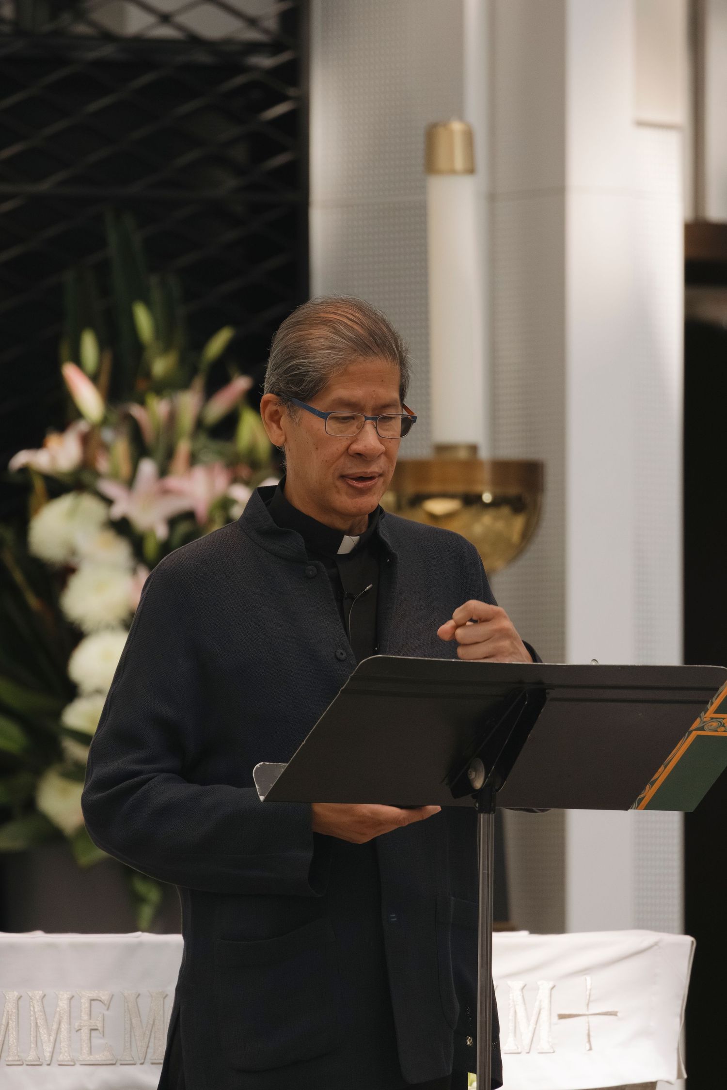Speaker reading from a music stand during a performance in an elegant venue.