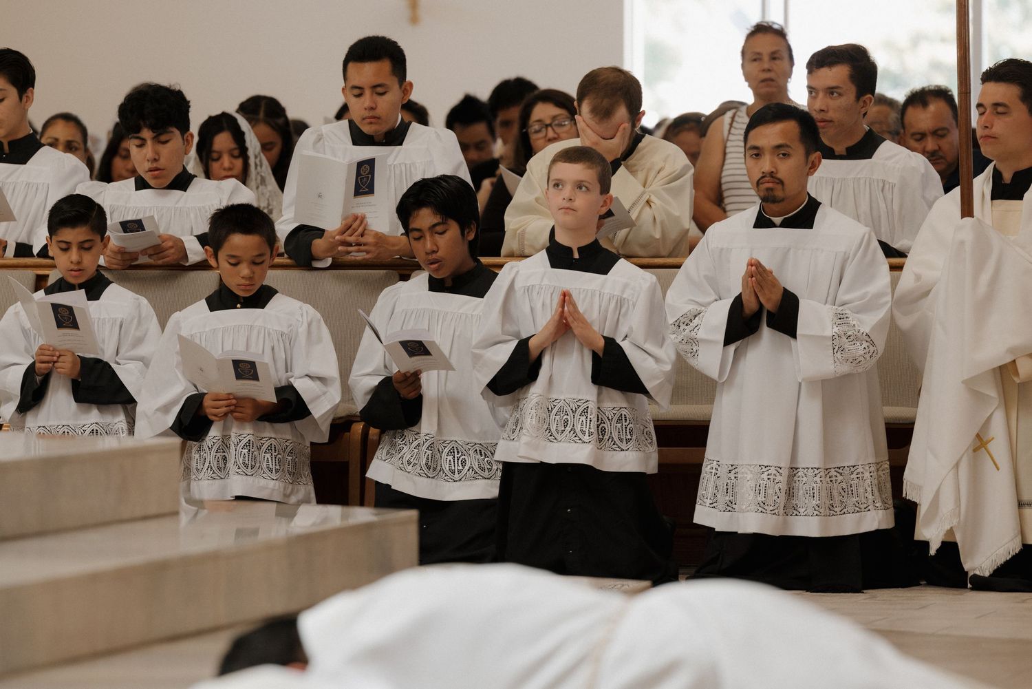 Group wearing white robes gathered in formal ceremony or service.