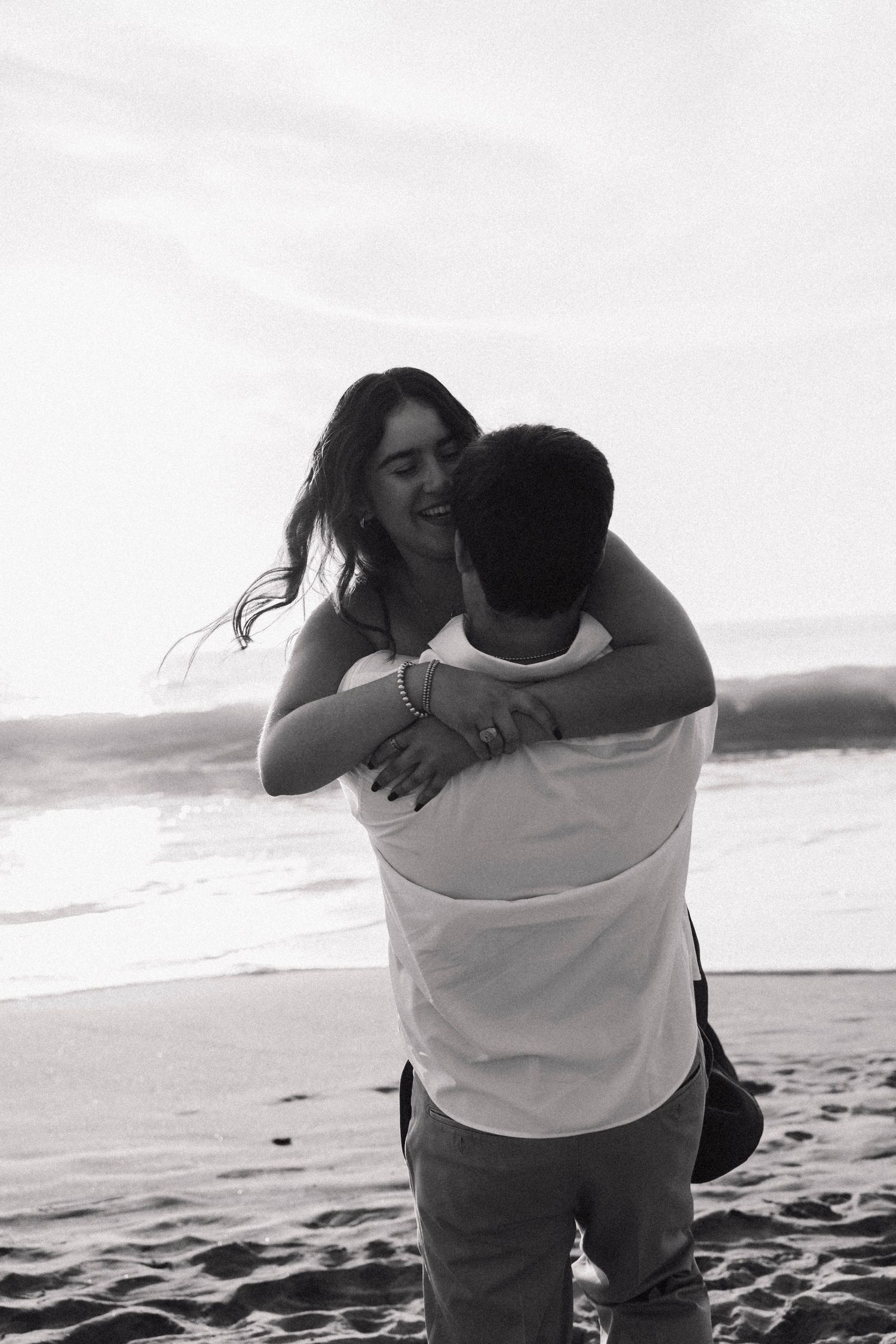 Couple embracing on a beach at sunset in black and white.