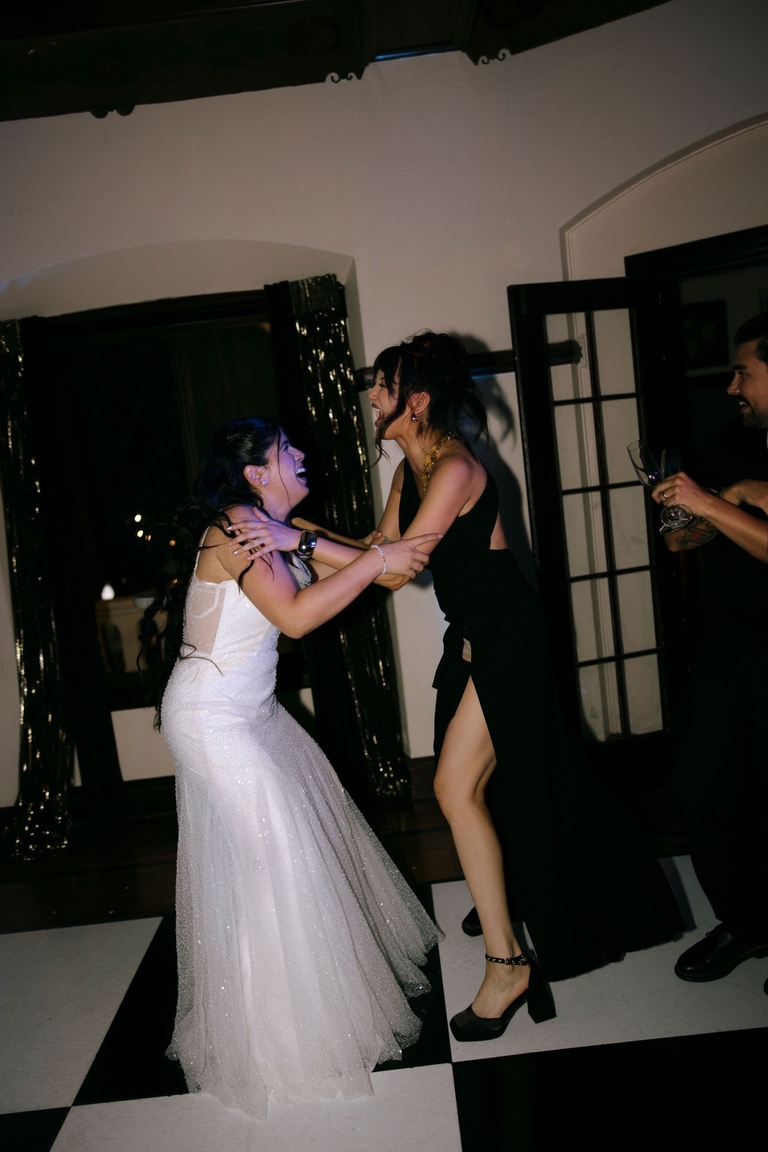 Two people dancing together at a wedding celebration on a black and white floor.