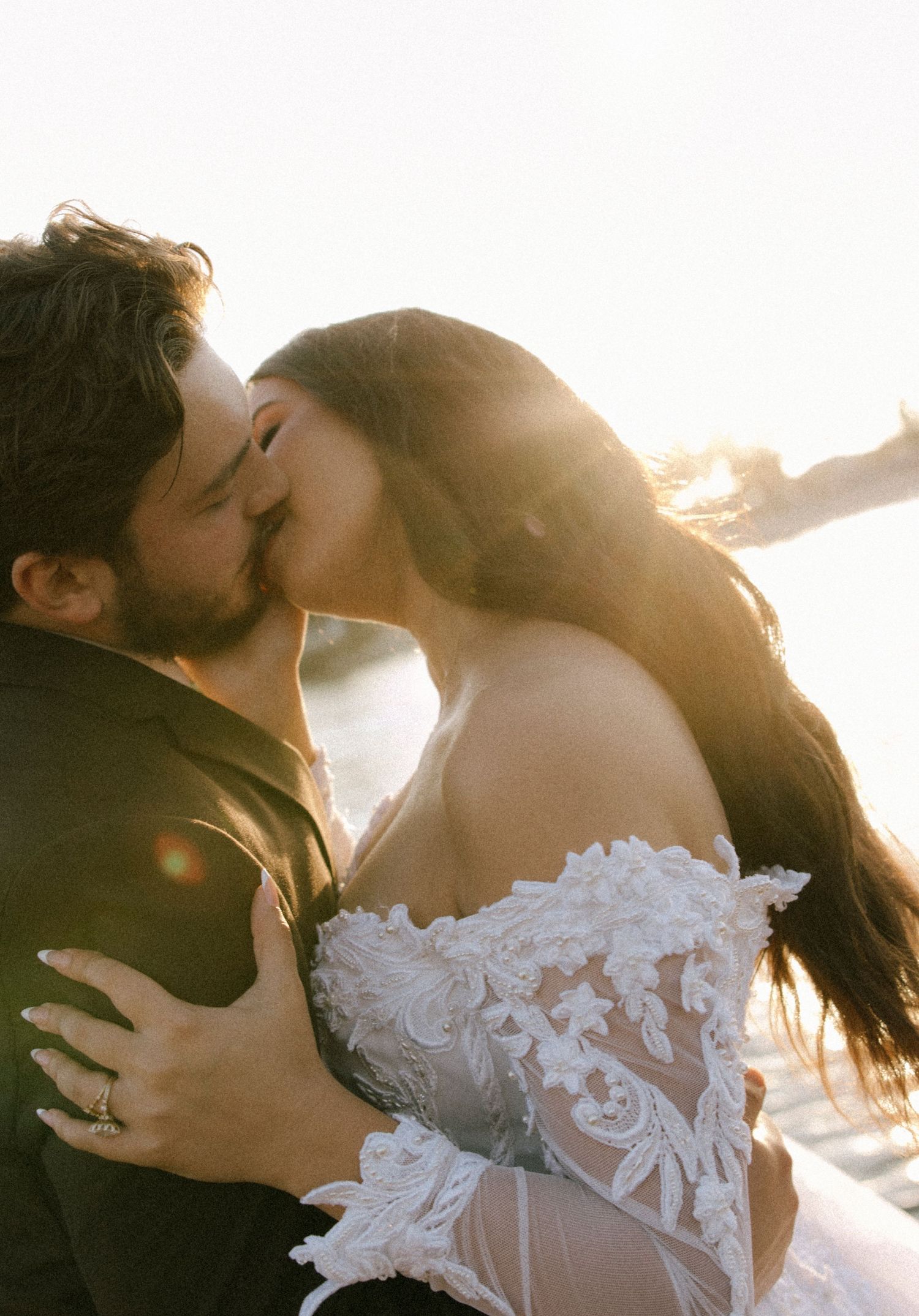 Romantic sunset kiss captured in golden light by the water.