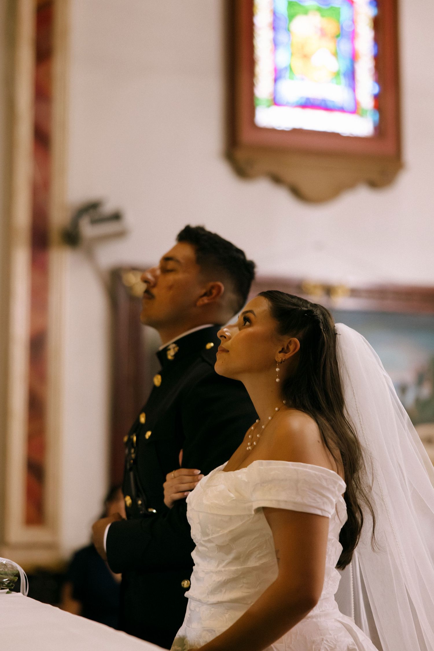 A bride and groom share a tender moment during their wedding ceremony in a traditional church setting.