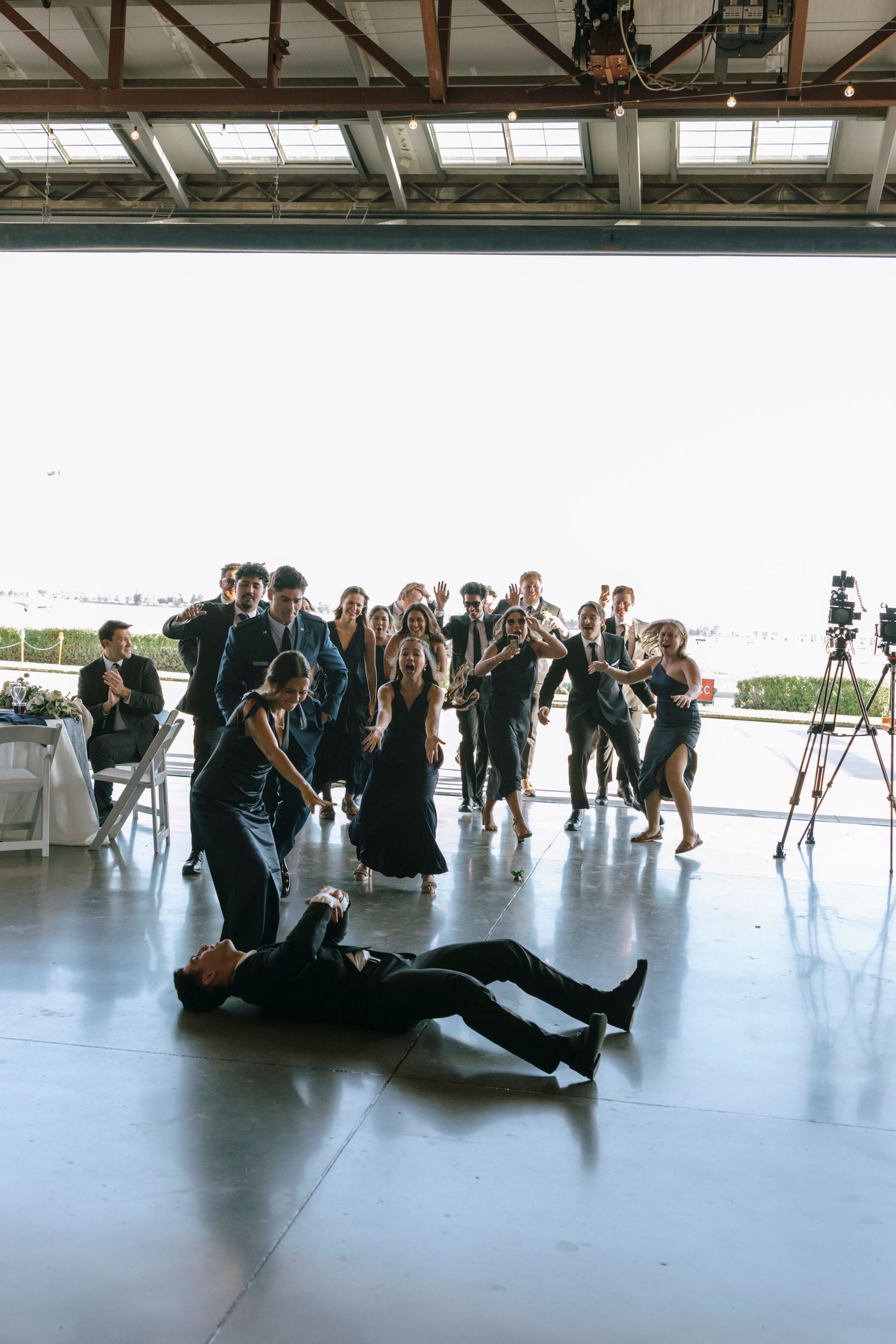 Wedding guests posing for group photos on the floor of a large indoor venue.
