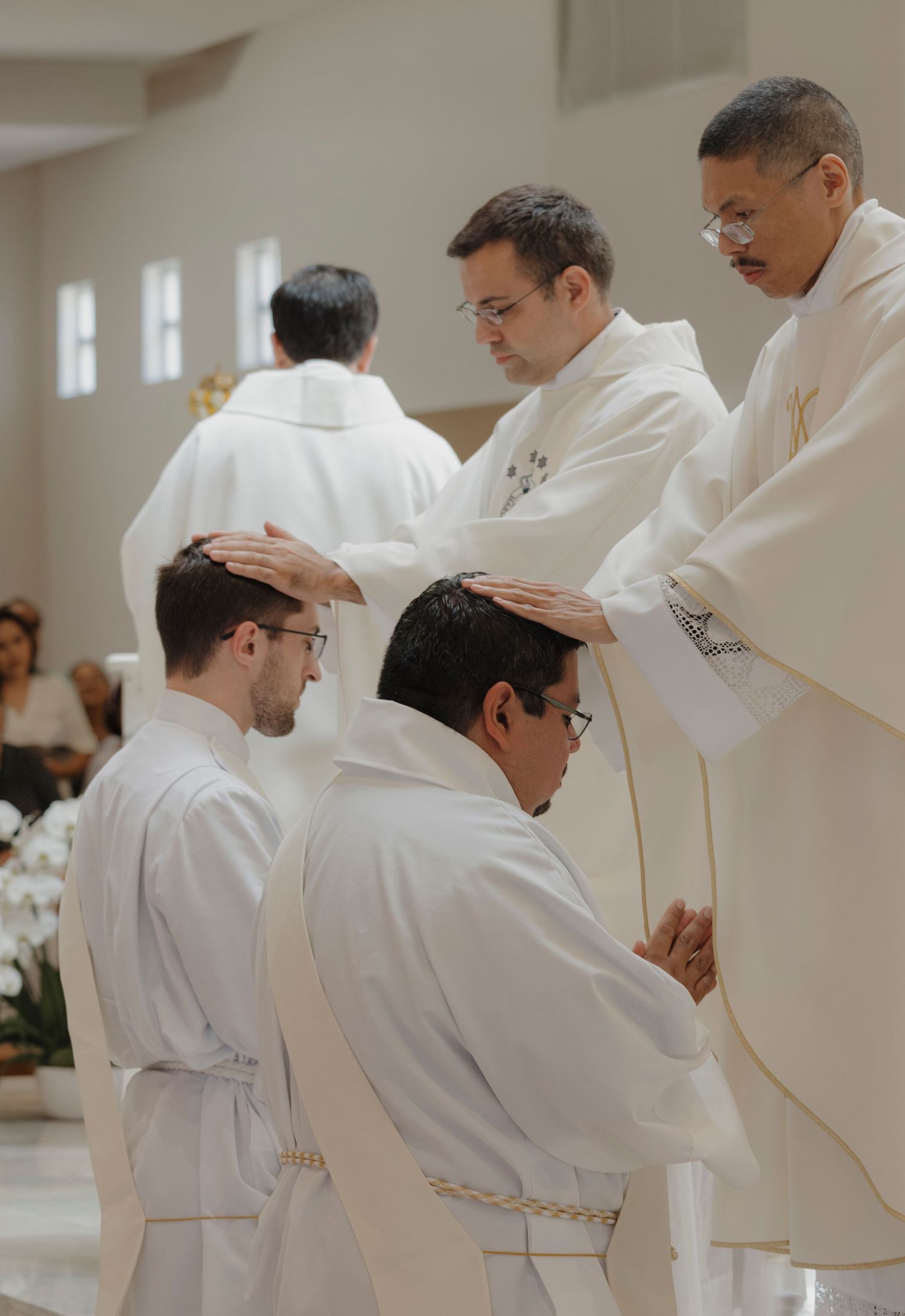 Clergy members in white robes perform a religious ritual.