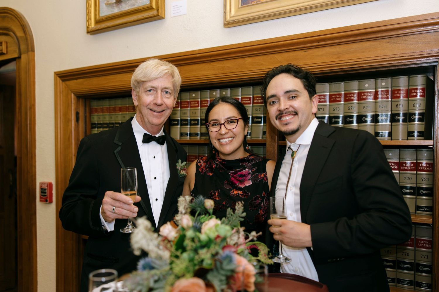 Formal gathering in a wood-paneled library with law books and elegant decor.