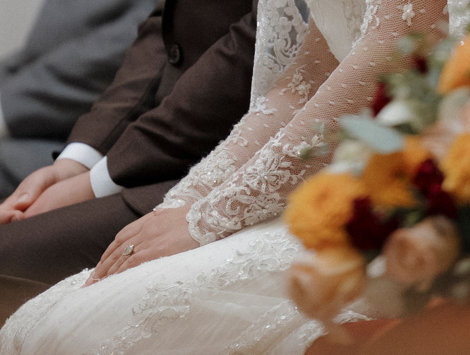 Detail shot of lace wedding dress and veil during church ceremony.