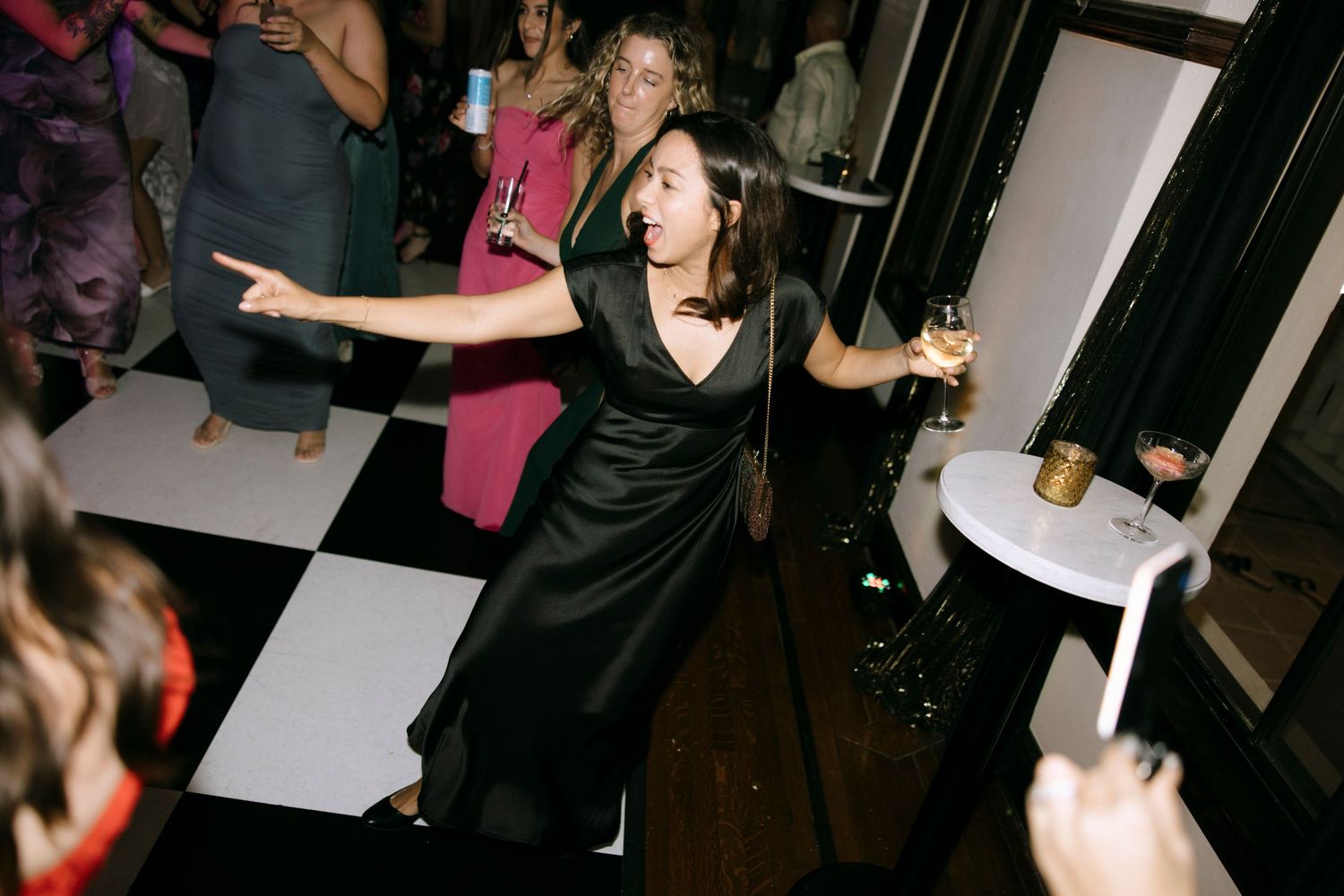 Guests dancing enthusiastically on a checkered dance floor at an evening celebration.