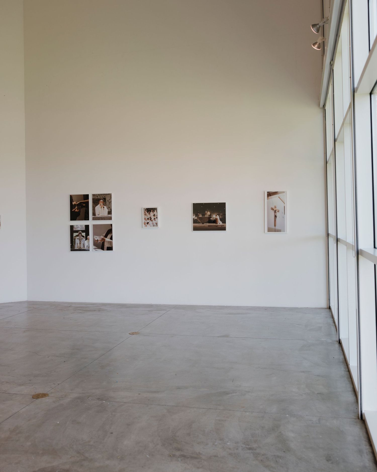 Modern gallery space with photographs mounted along windowed wall.