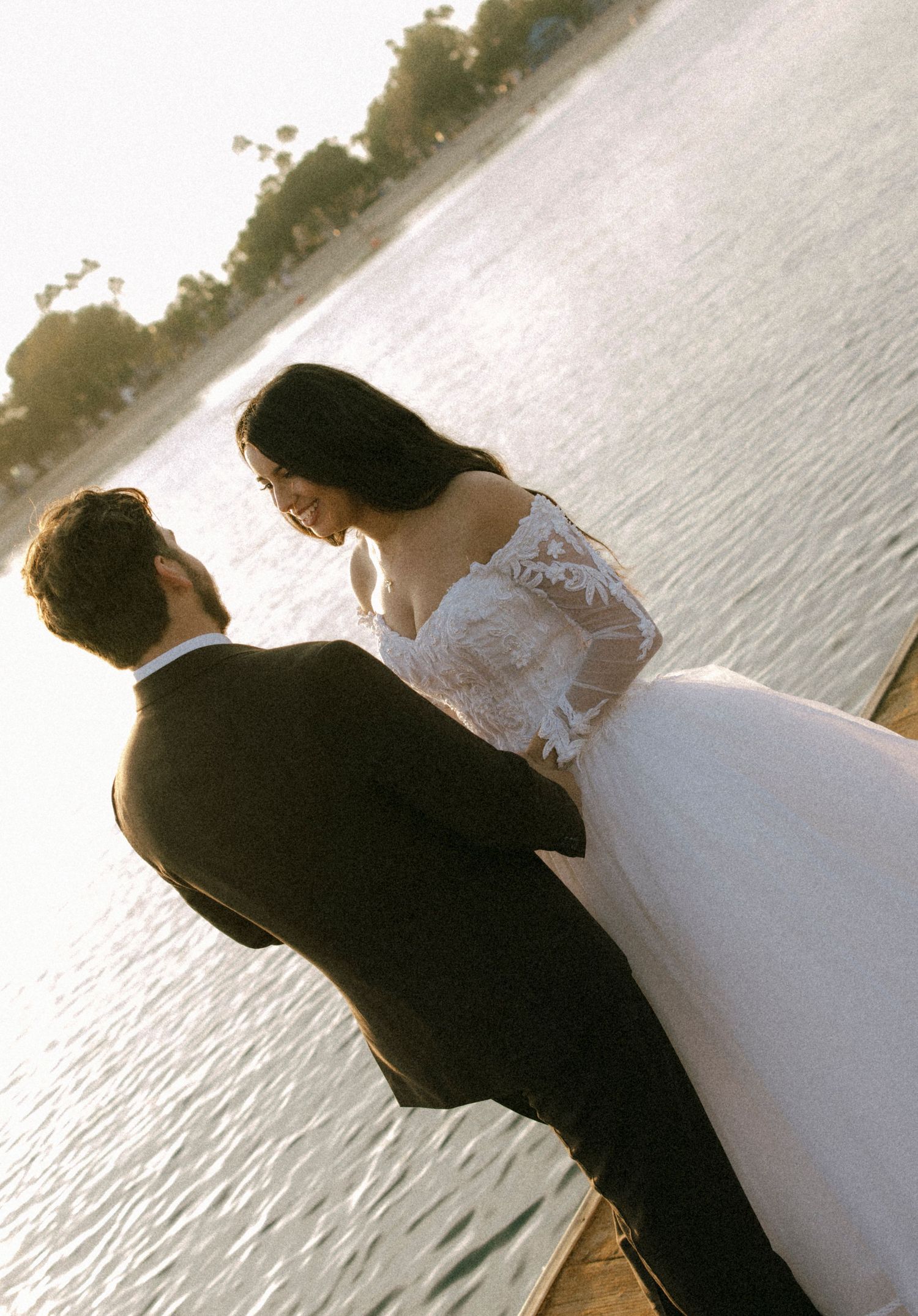 Silhouetted wedding couple against a serene waterfront at sunset.