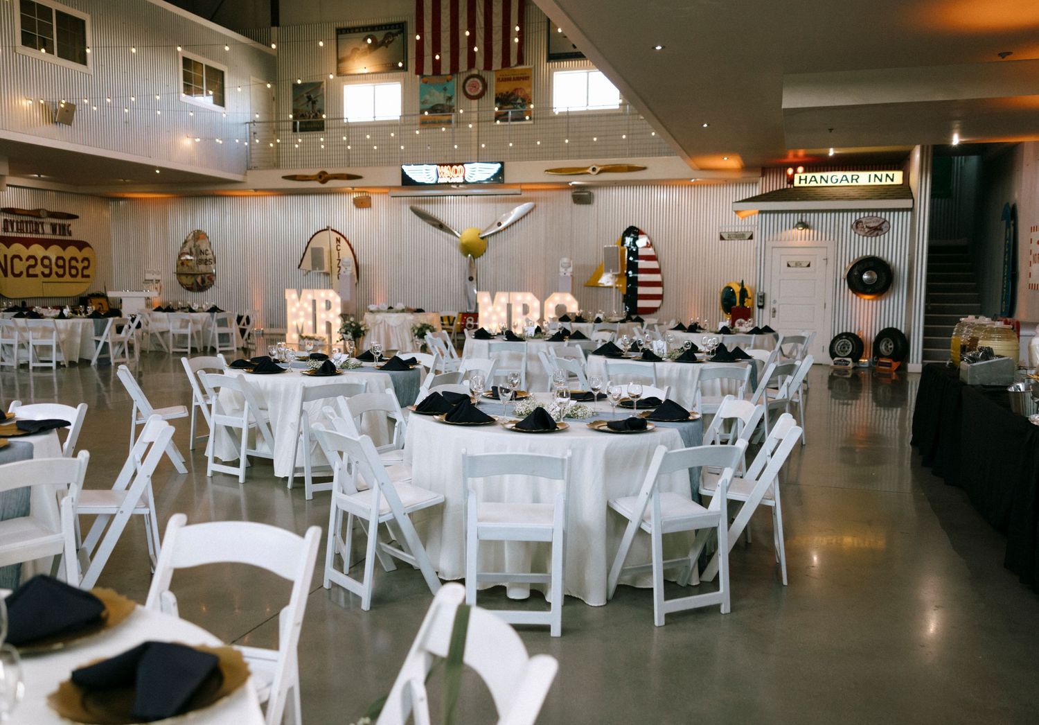 Wedding reception hall decorated with white chairs and tables set for a formal celebration.