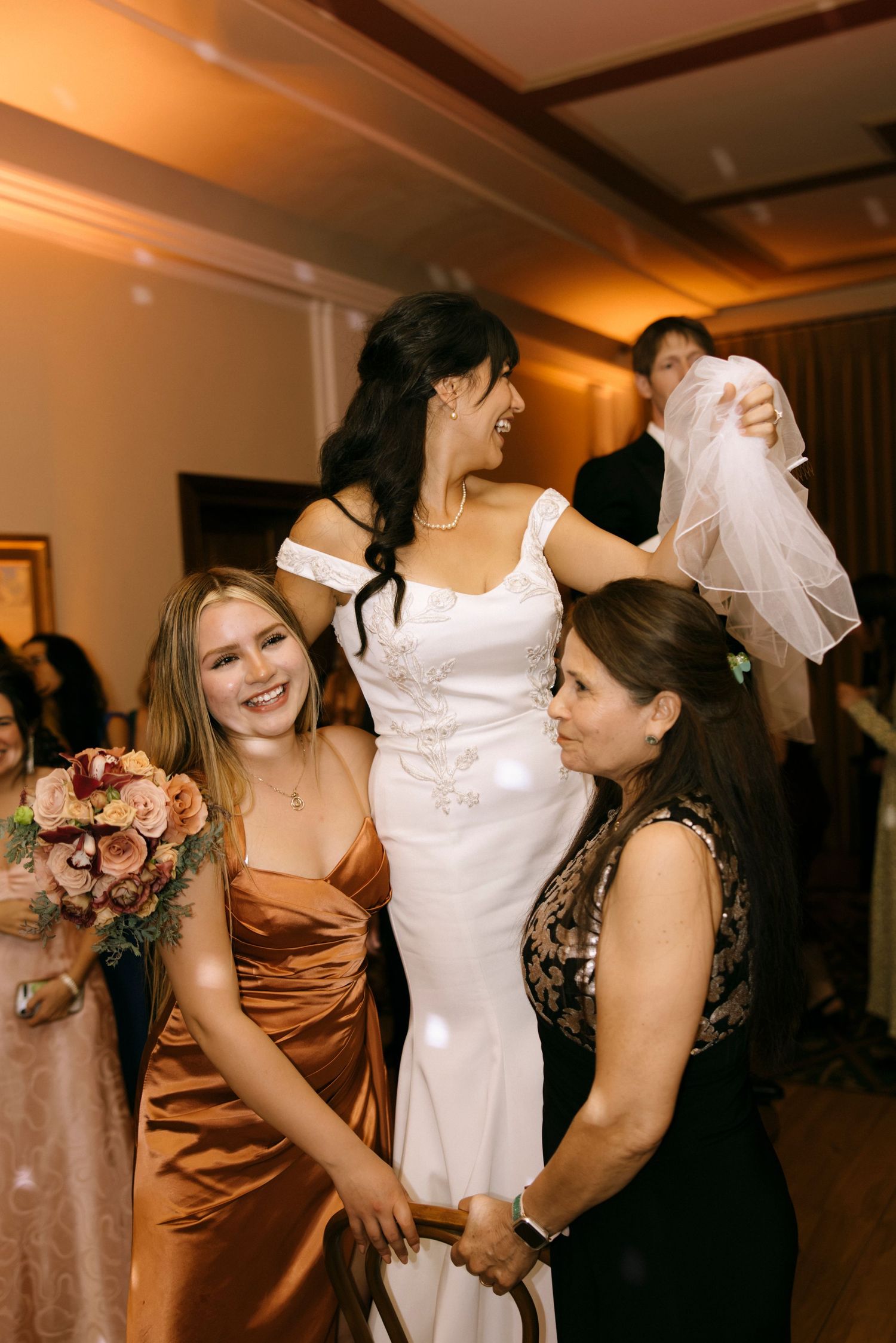 Wedding guests in formal attire dance and celebrate at an indoor reception.