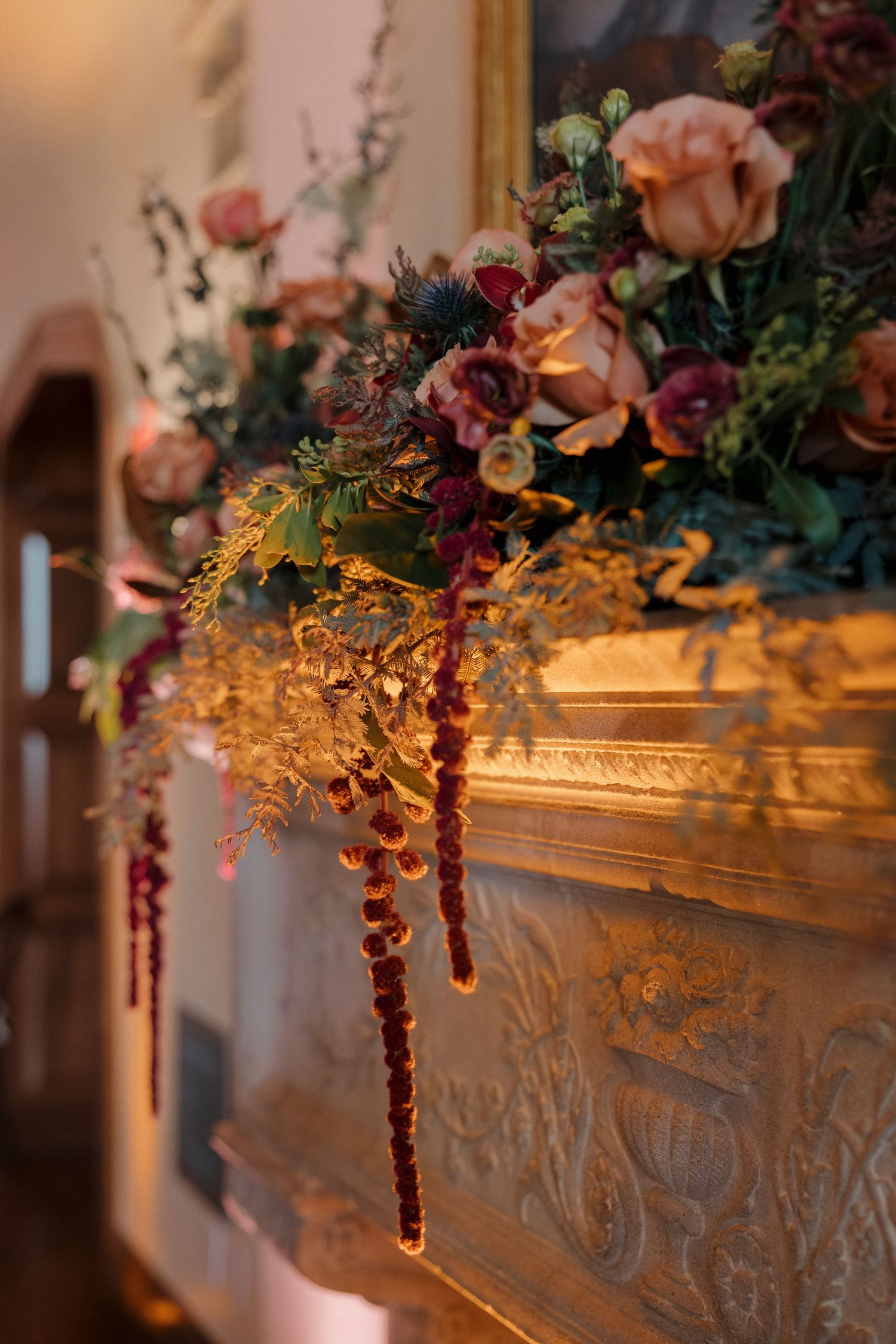 Ornate golden mantelpiece decorated with lush floral arrangements in warm autumn colors.
