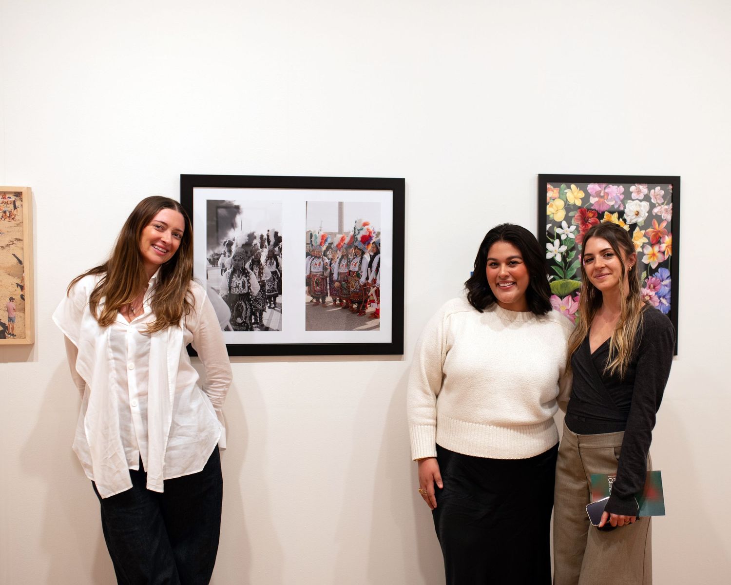 Gallery visitors pose in front of artwork display at museum exhibition.