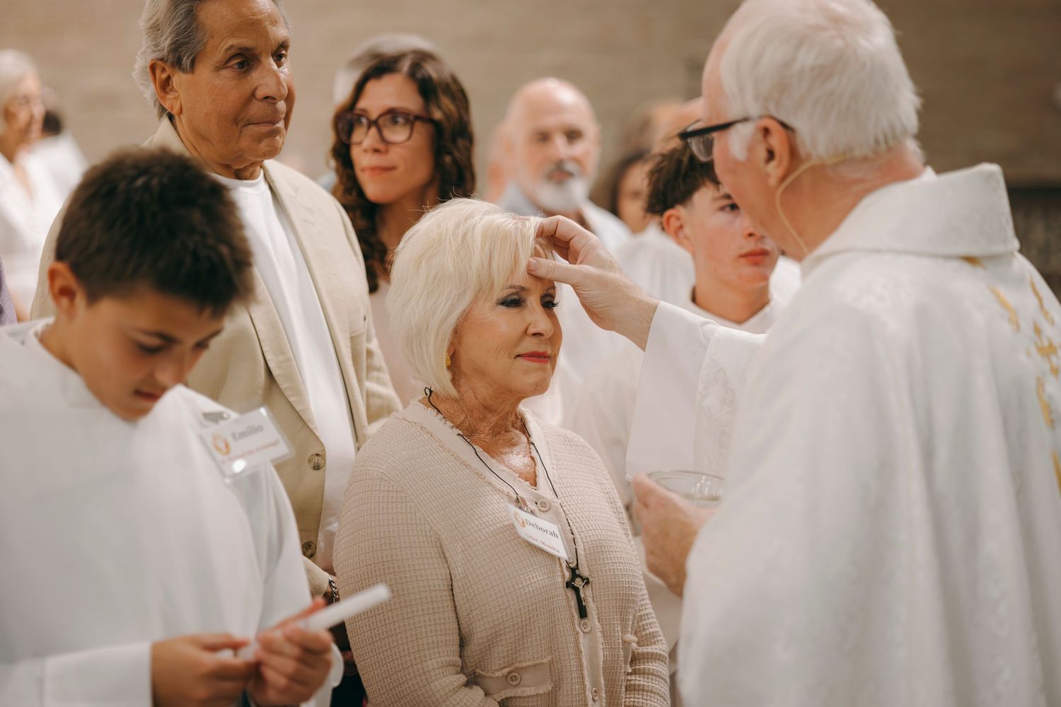 Priest anointing a woman with oil during a Catholic confirmation or anointing ceremony in church.