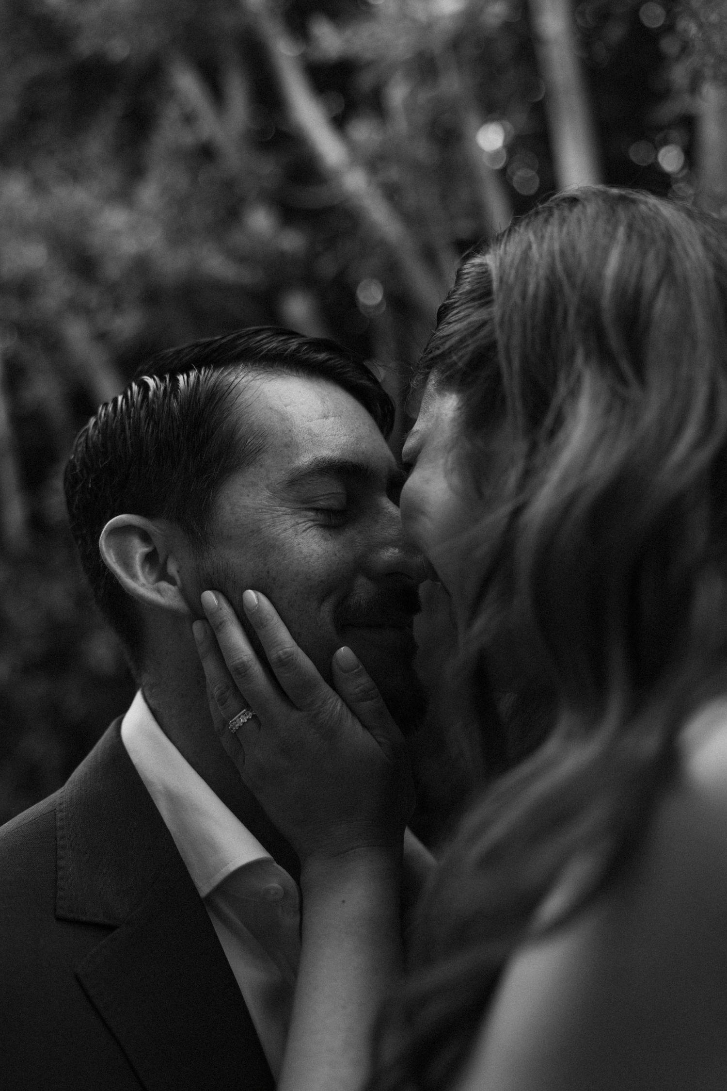 Black and white romantic photo of a couple sharing an intimate moment, woman gently cupping mans face.