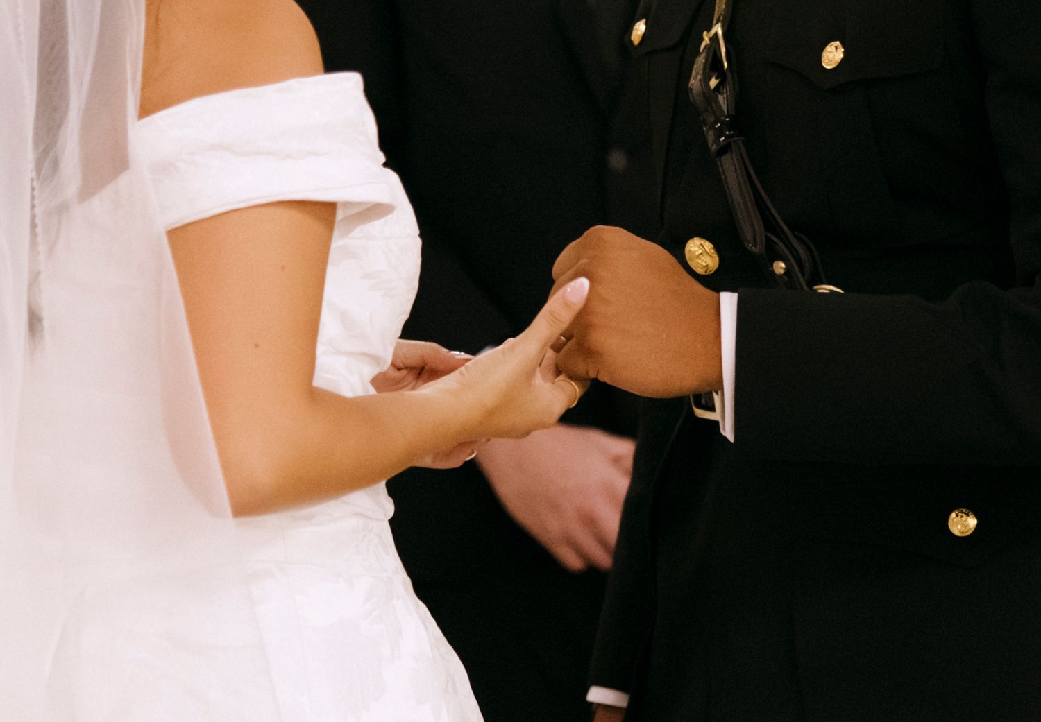 Close-up of hands exchanging rings during a military wedding ceremony.