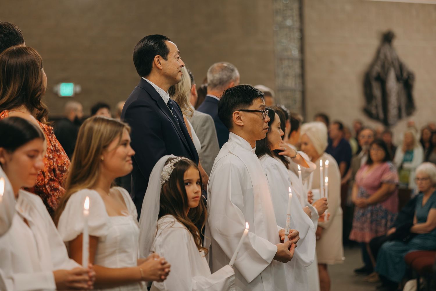 Congregation holding candles during a Catholic church baptism ceremony.