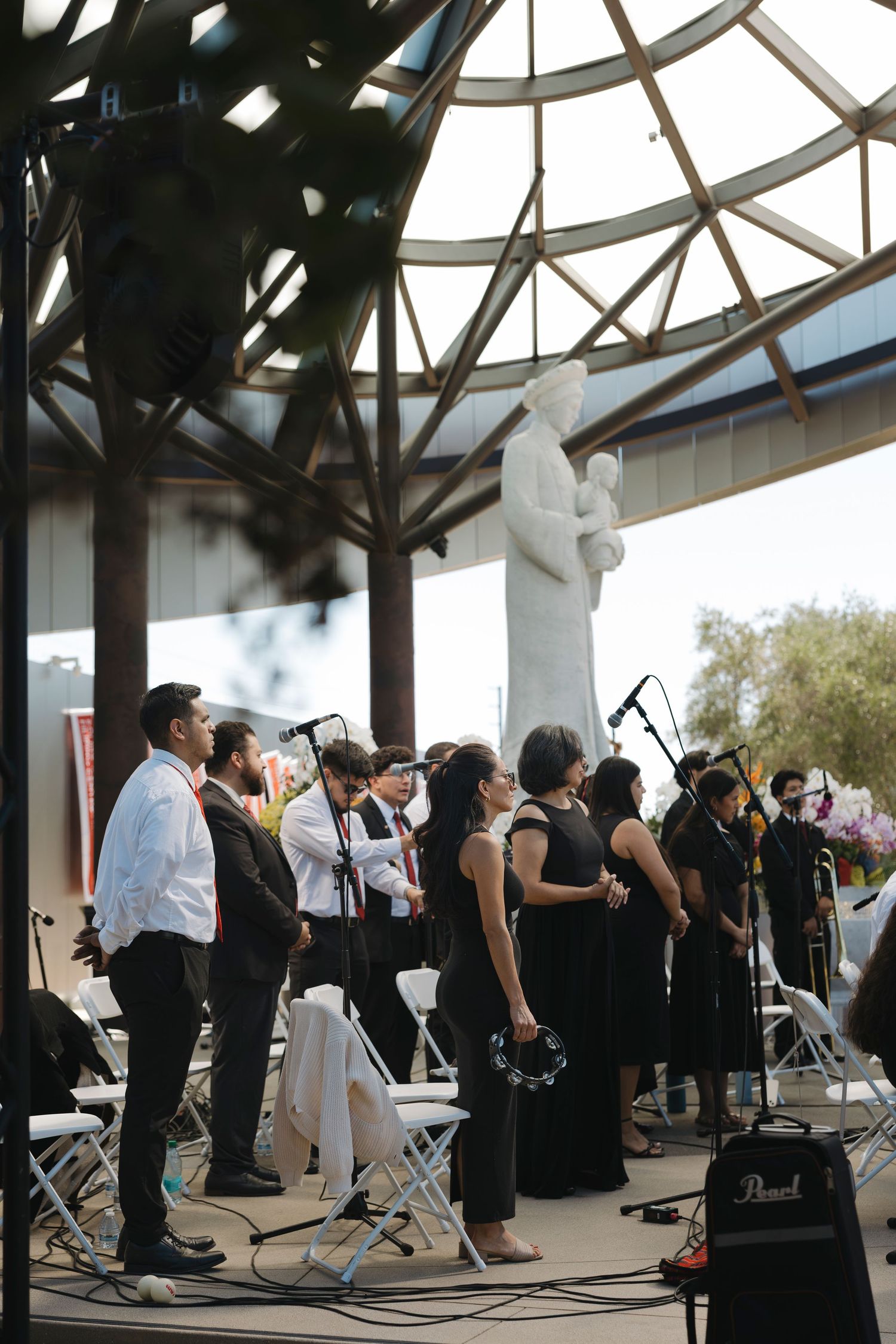 Orchestra performers in black and white attire playing under a domed glass ceiling.