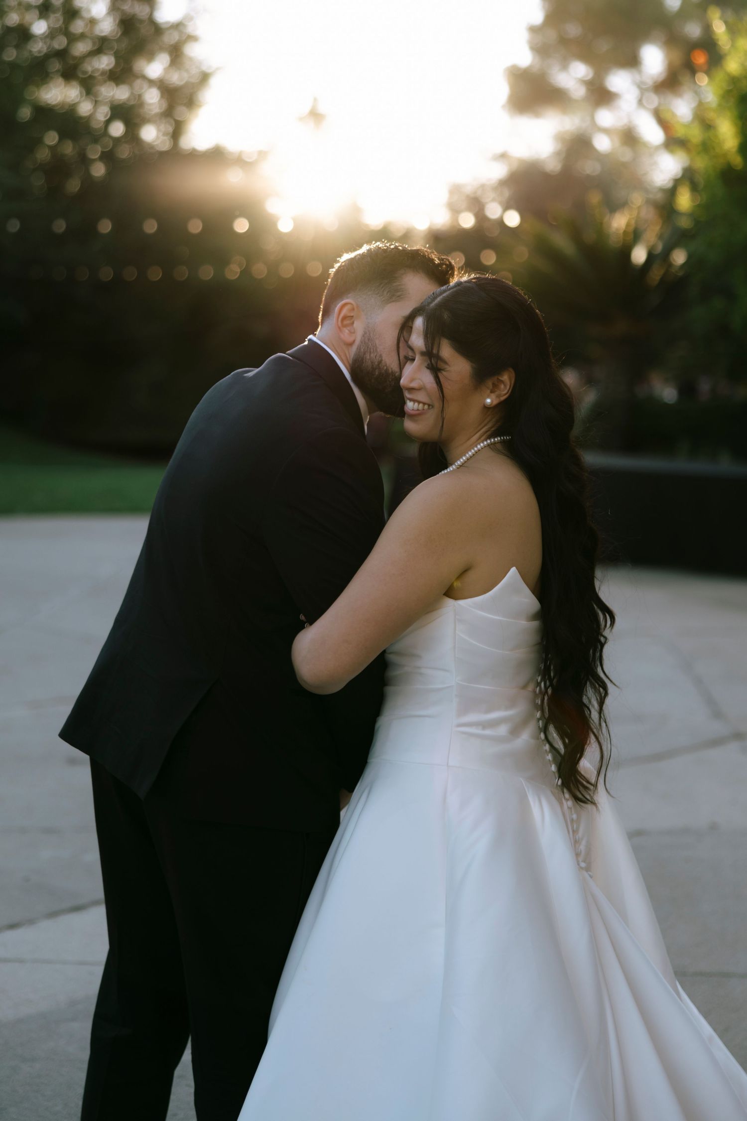 Sunset wedding portraits with golden light creating silhouettes against natural backdrop.
